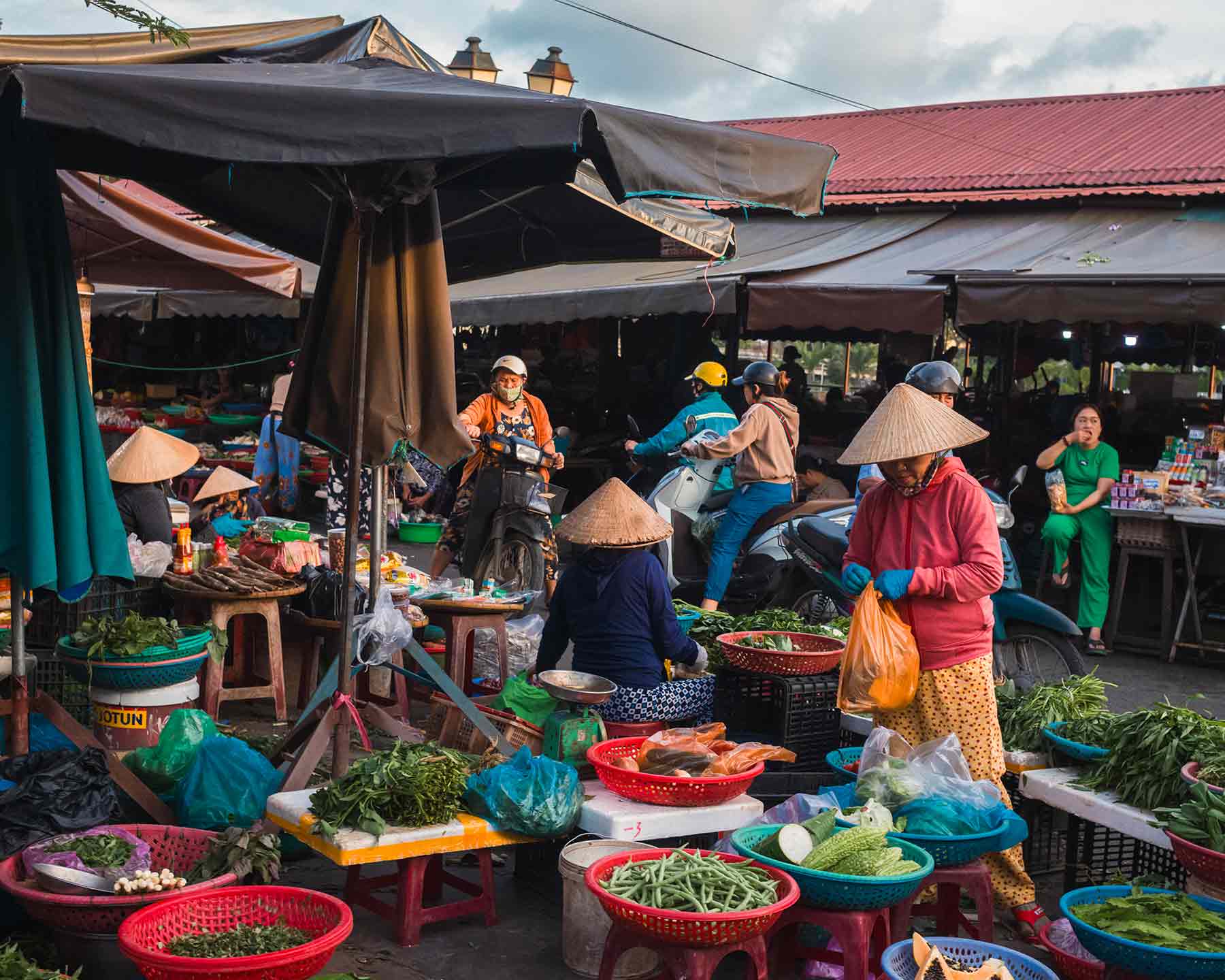 Bustling Hoi An Vietnam market with fresh produce and traditional architecture.