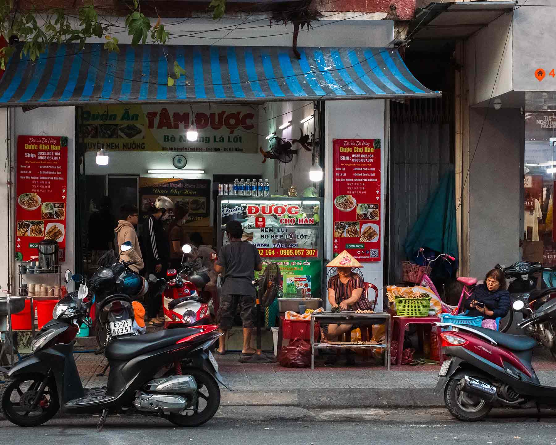 Motorbikes parked at a bustling food storefront in Hanoi Vietnam.