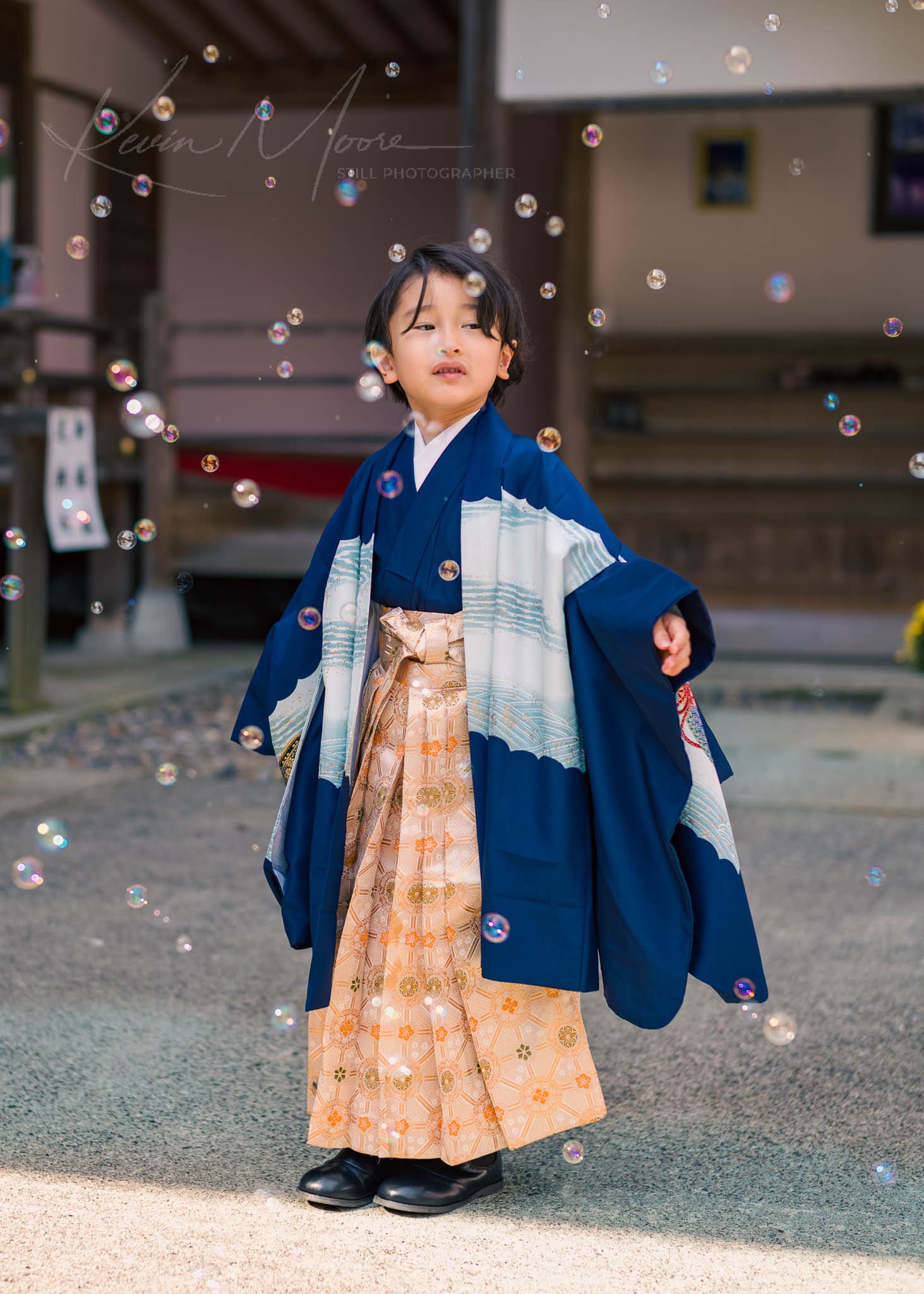 Child in traditional Japanese attire playing with bubbles outdoors.