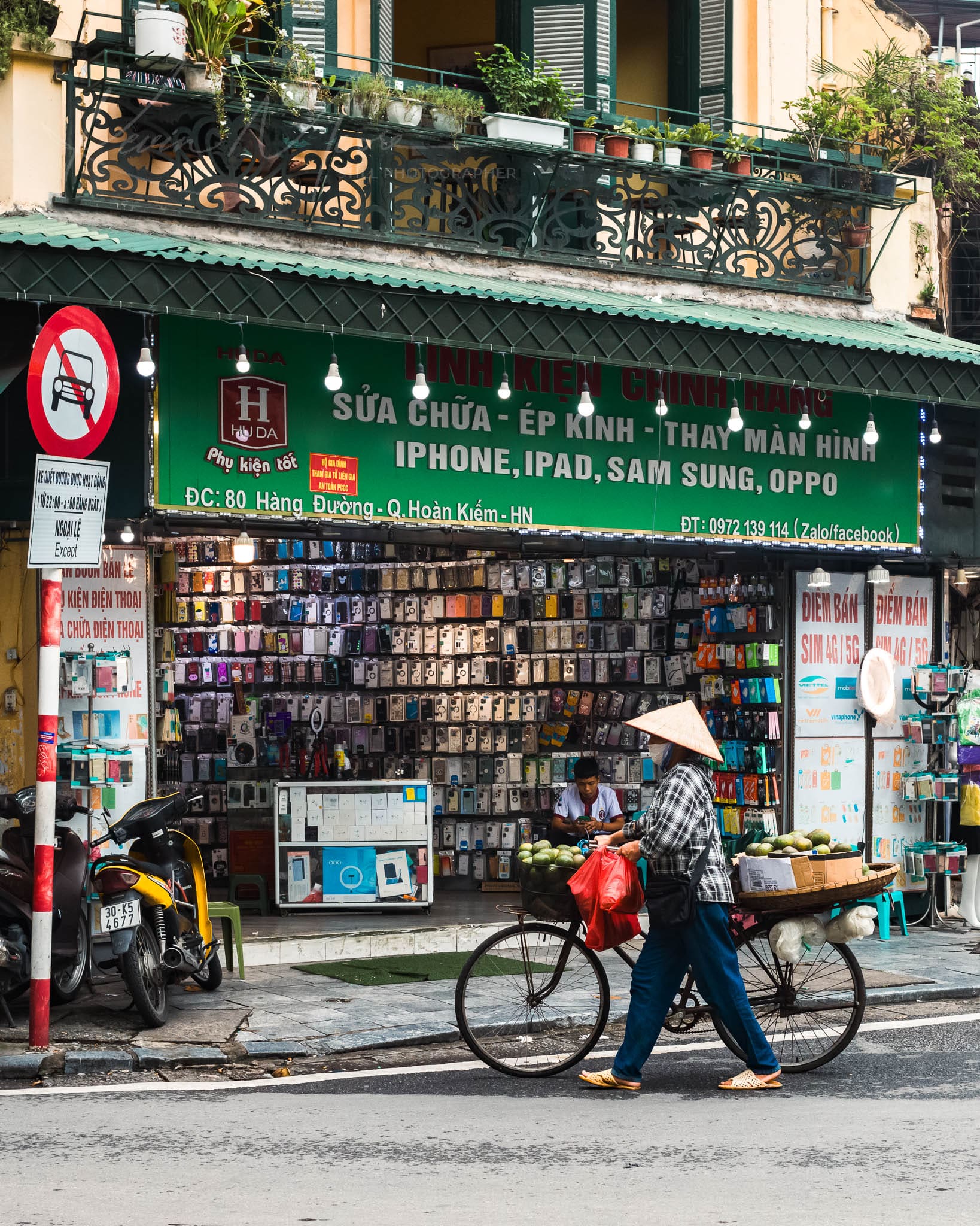 Hanoi Vietnam electronics shop with vibrant phone cases and traditional street vendor.