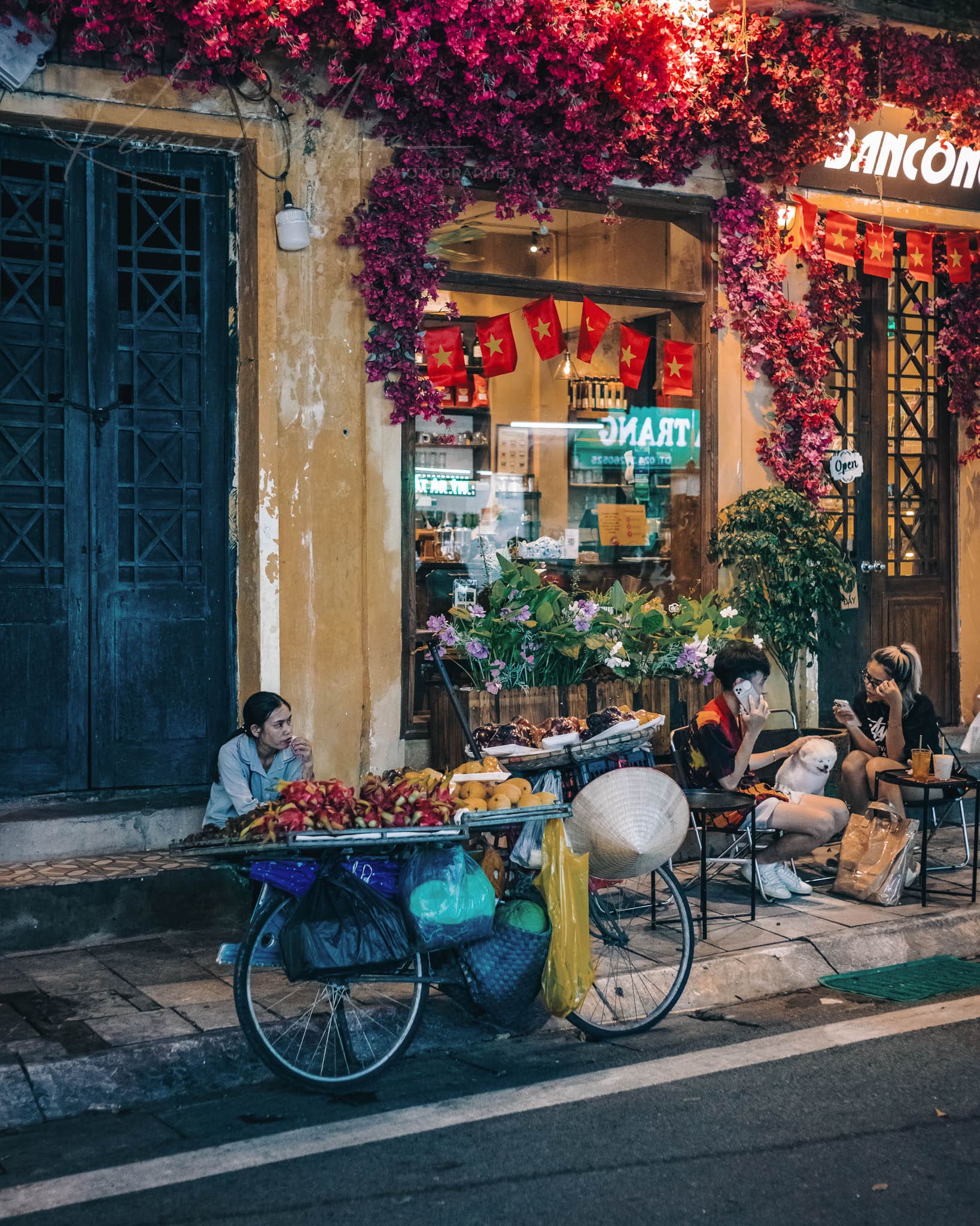 Traditional fruit cart in a lively Hanoi street market during evening.