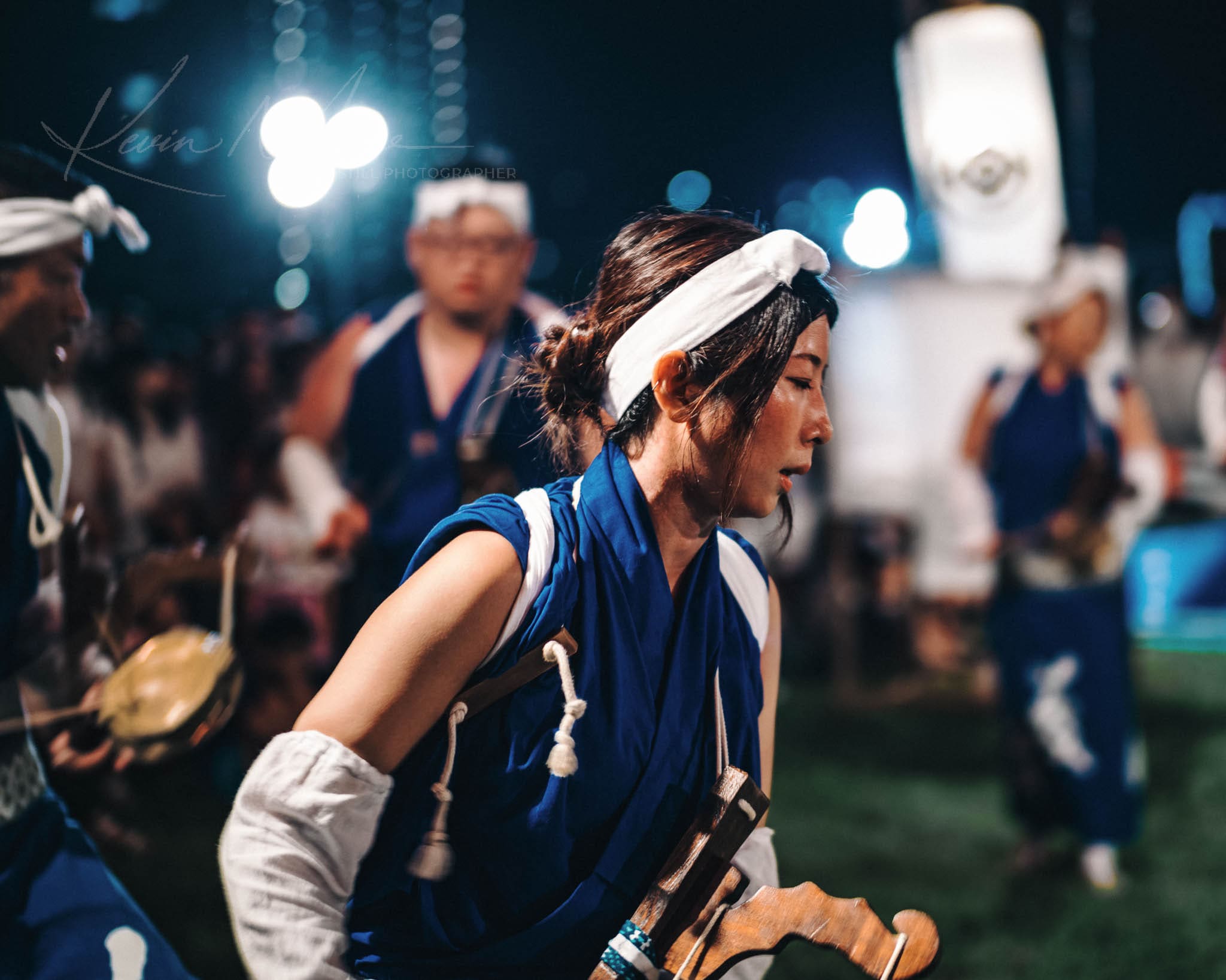 Focused Yukata-clad performer in action at a vibrant Japanese matsuri festival at night.