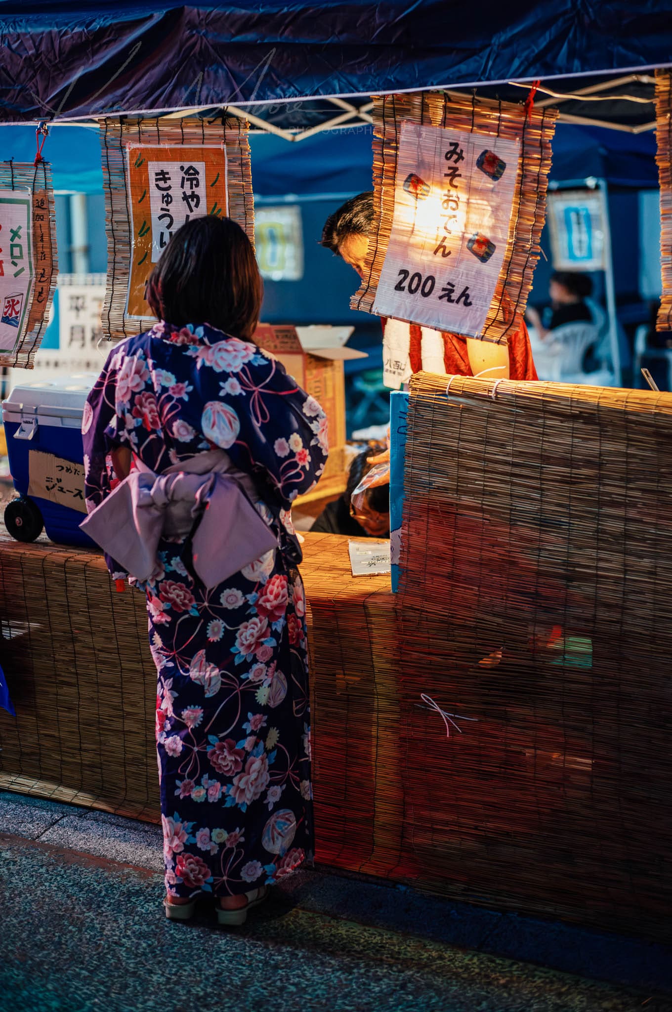Person in Yukata Shopping at Illuminated Japanese Market Stall in Dusk Setting