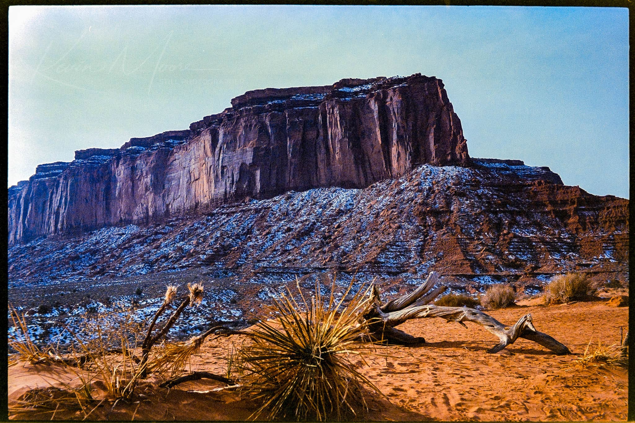 Majestic mesa amidst rugged desert vegetation under clear blue sky.