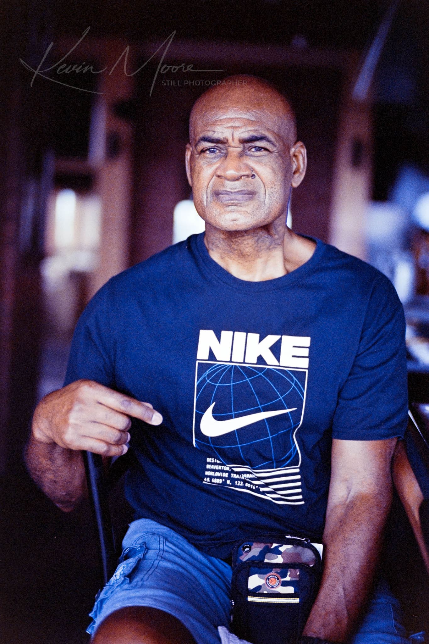 Confident mature man pointing at Nike logo on his t-shirt indoors.