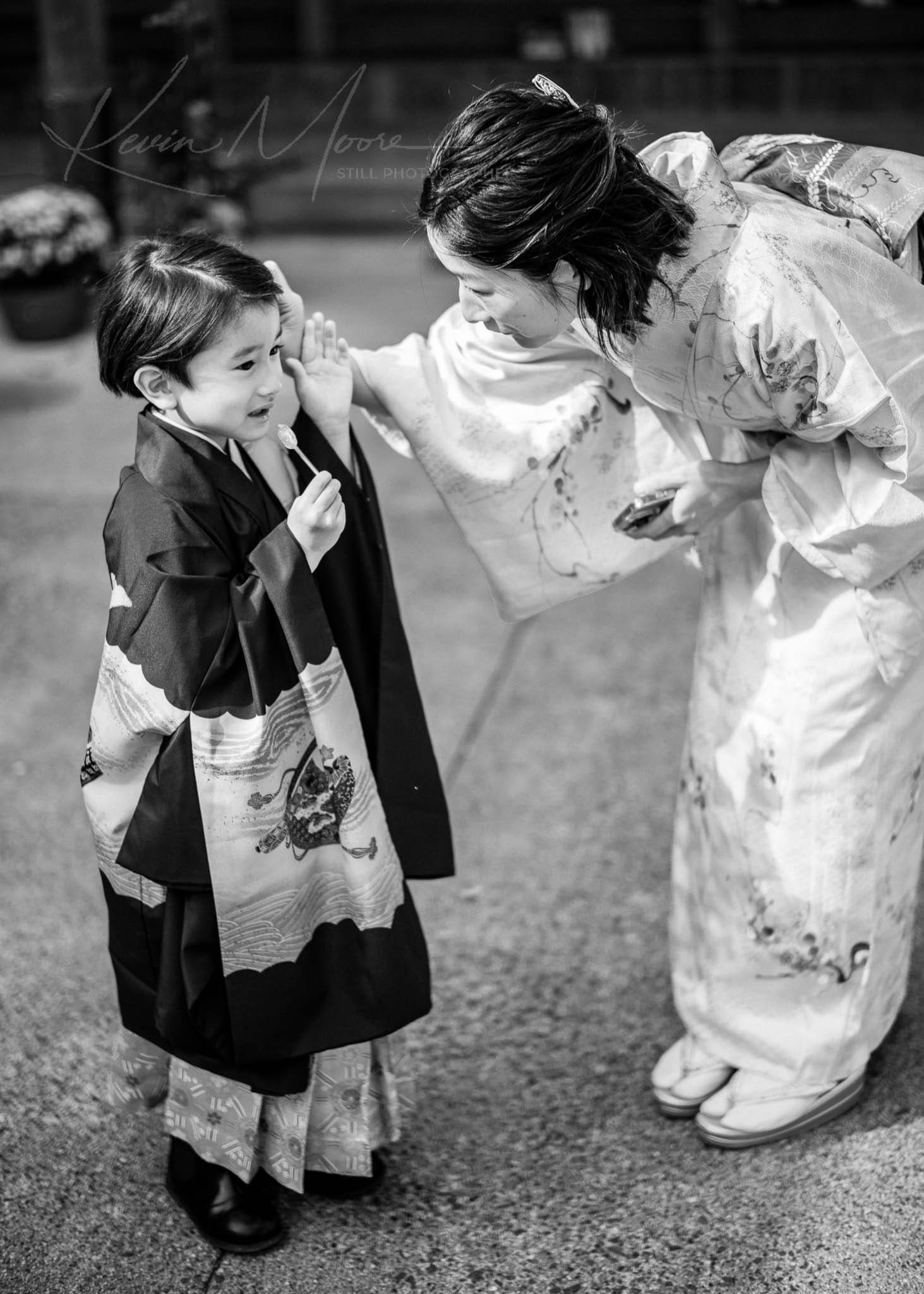 Traditional Japanese mother and child sharing intimate moment outdoors in black and white.