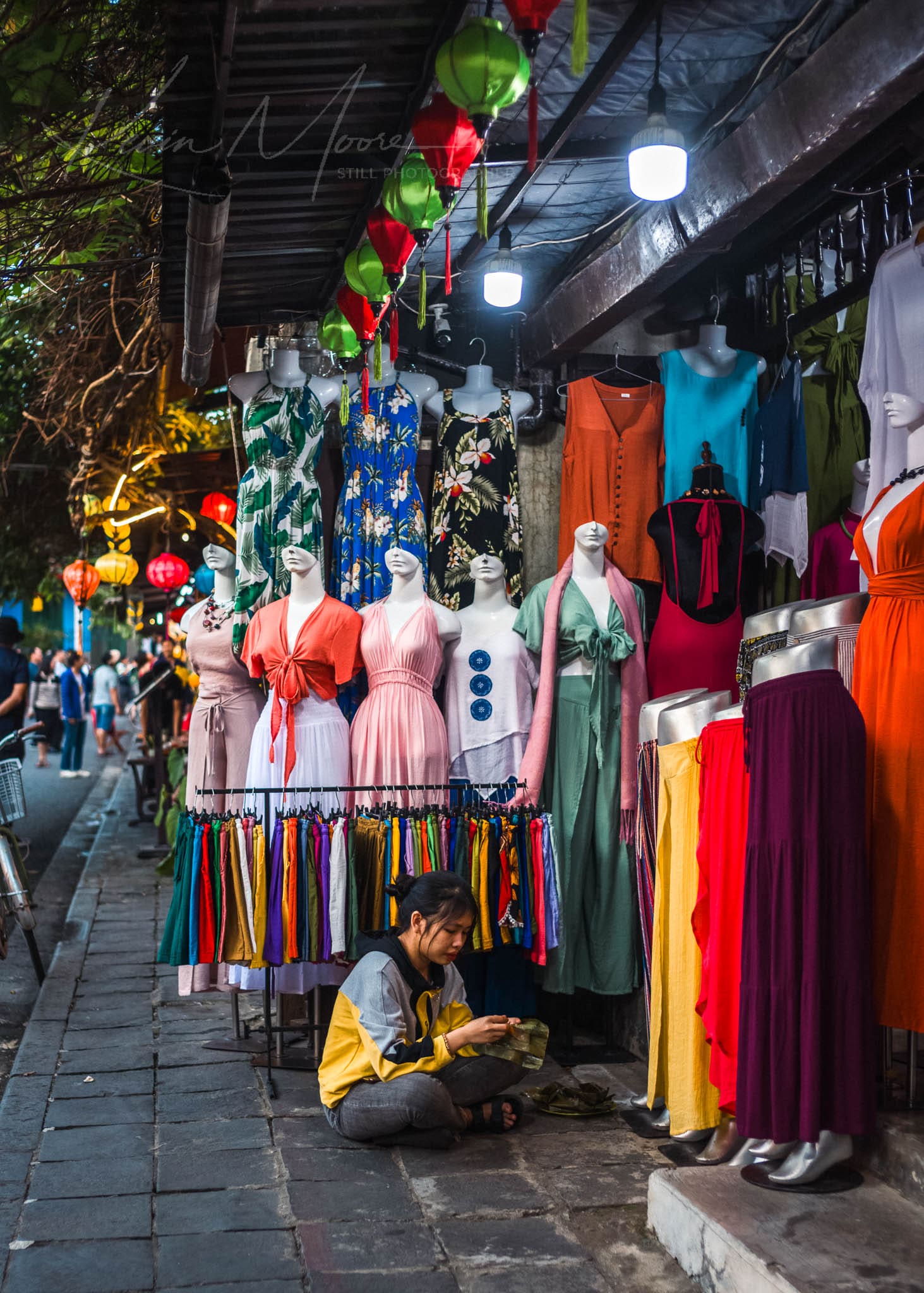 Colorful traditional dresses on mannequins in vibrant night market scene.