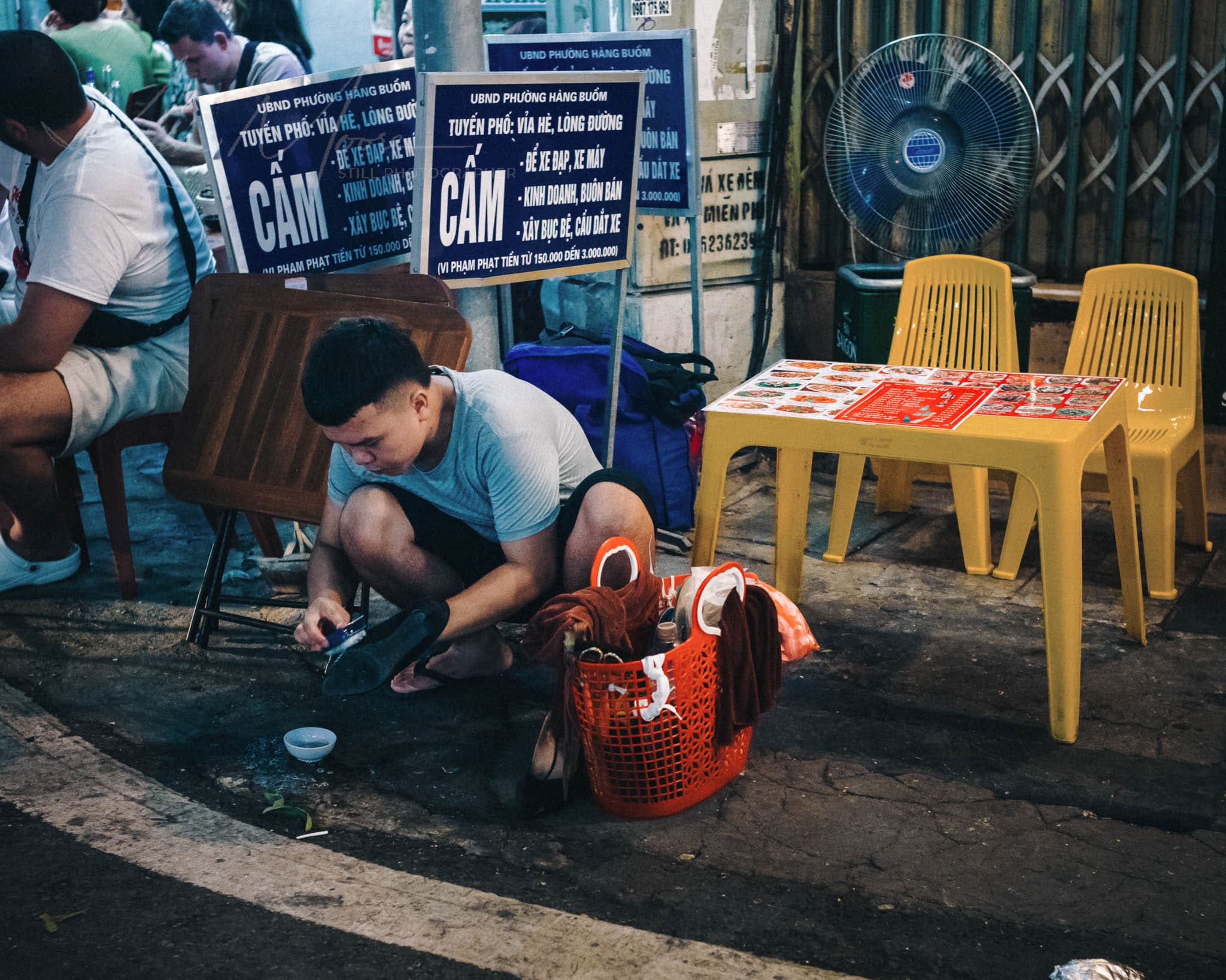 Night street scene with man cleaning shoes in urban Hanoi Vietnam