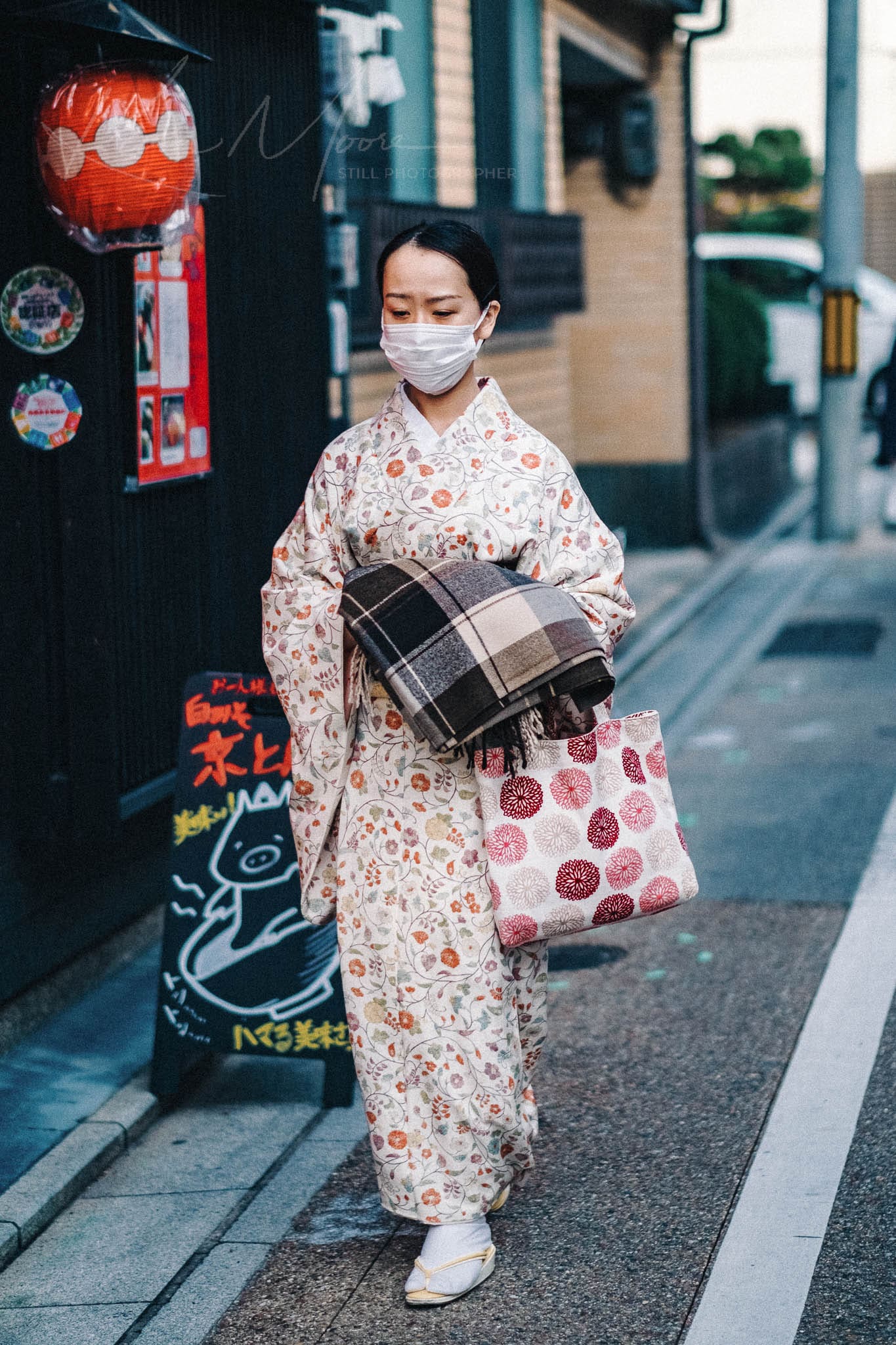 Woman in floral kimono and face mask navigating traditional-modern Kyoto.