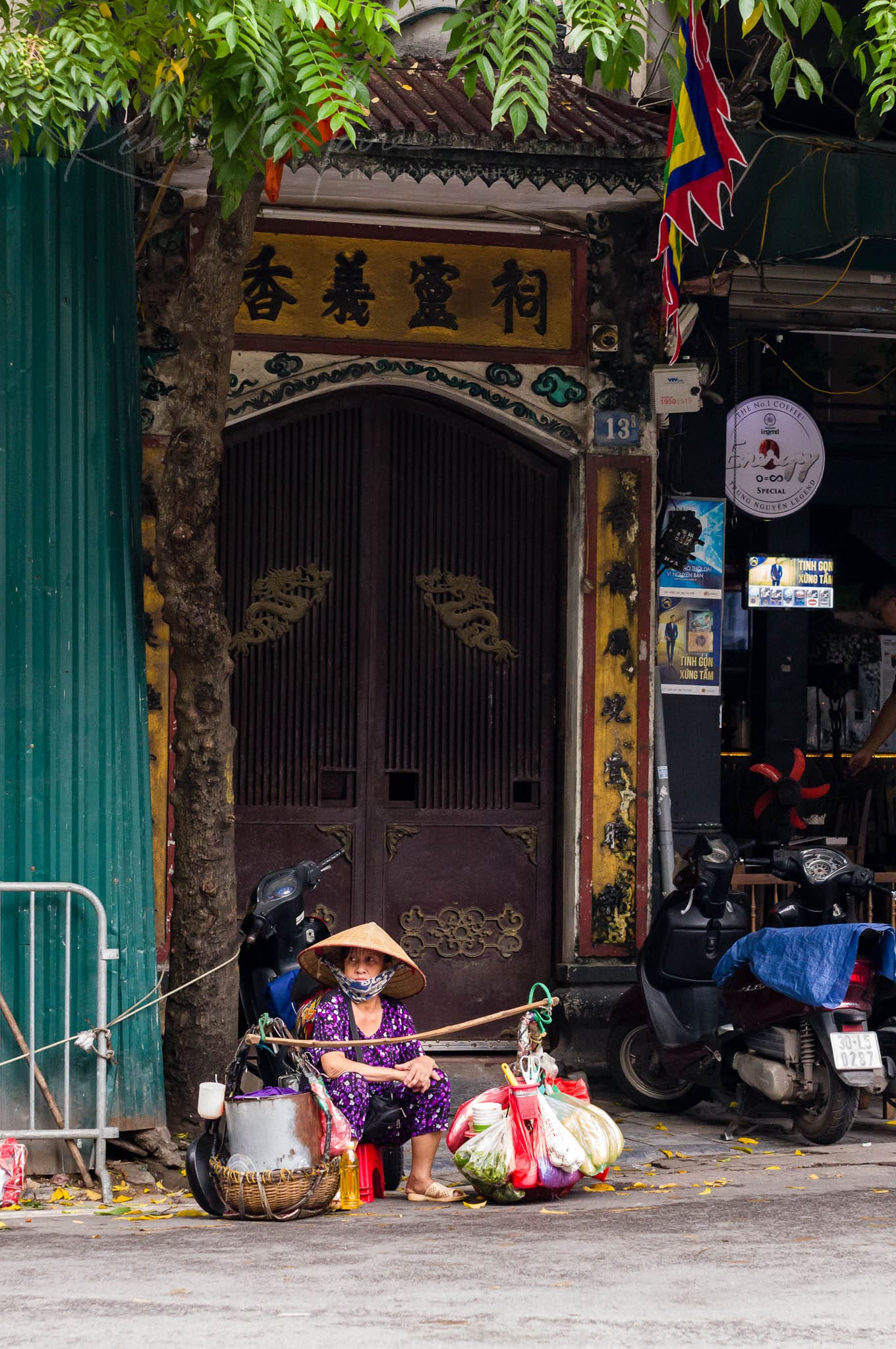 Traditional Vietnamese vendor preparing goods in a historical Southeast Asian street setting.