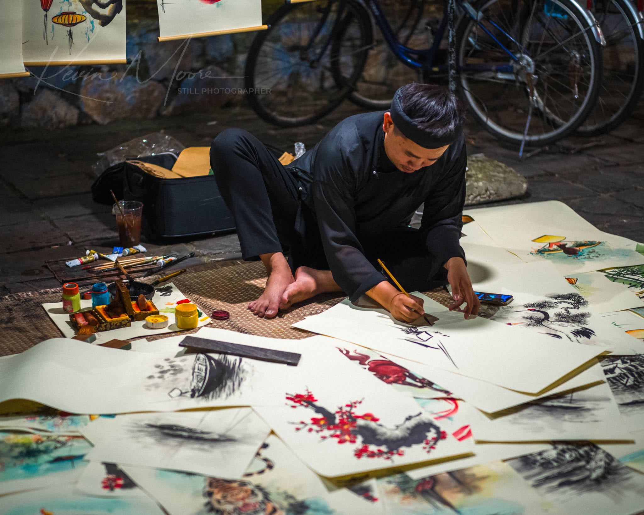 Traditional artist creating East Asian ink wash paintings in a public setting.