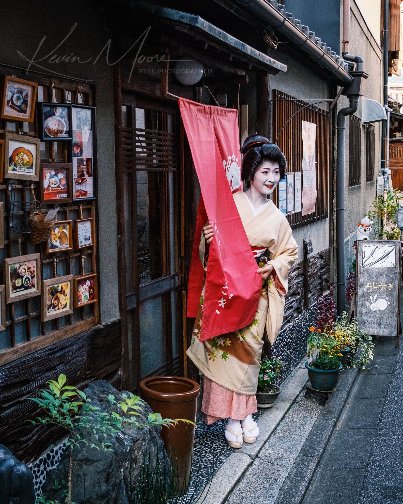 Geisha in kimono holding banner in historic Japanese alleyway