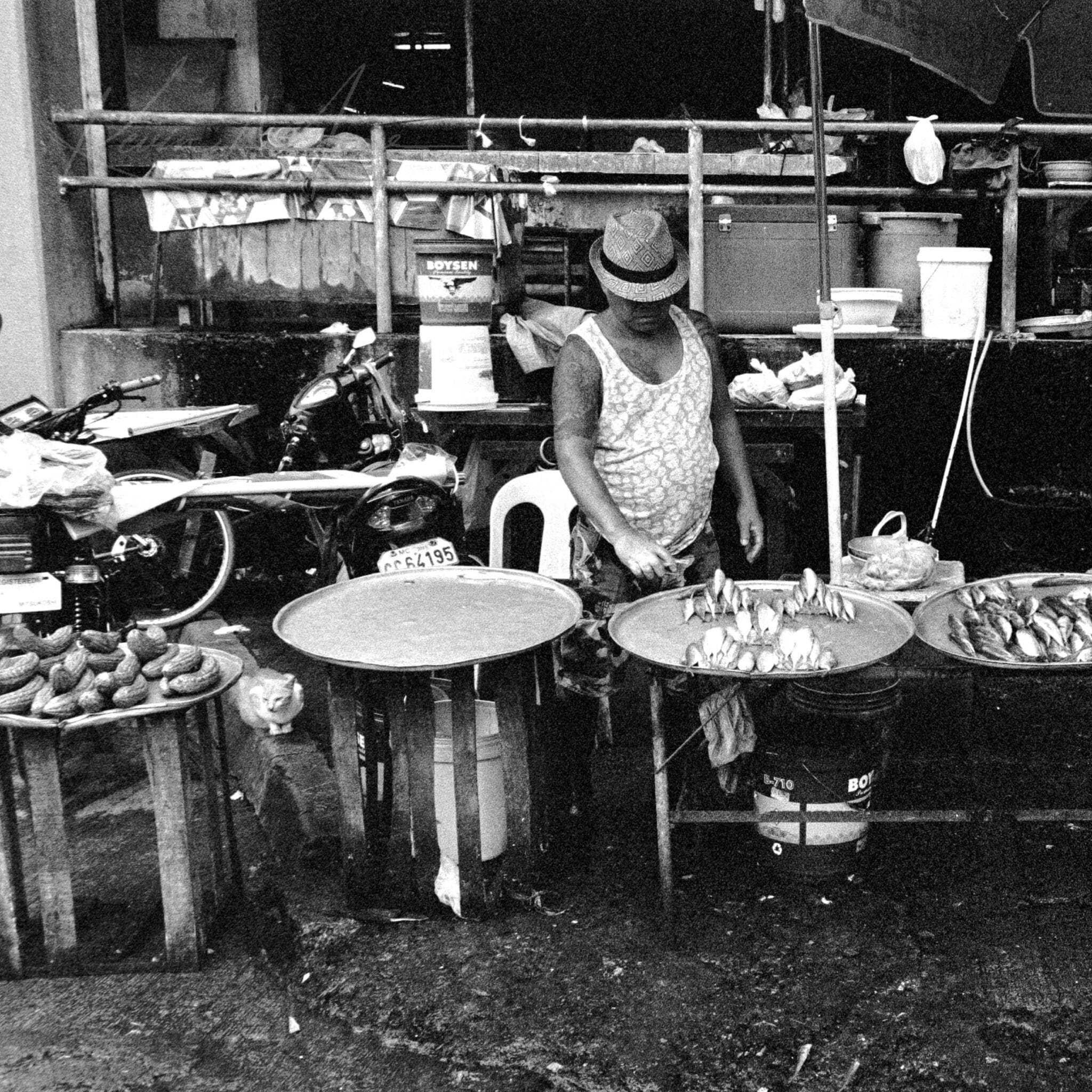 Local vendor preparing food at a traditional outdoor market stall.