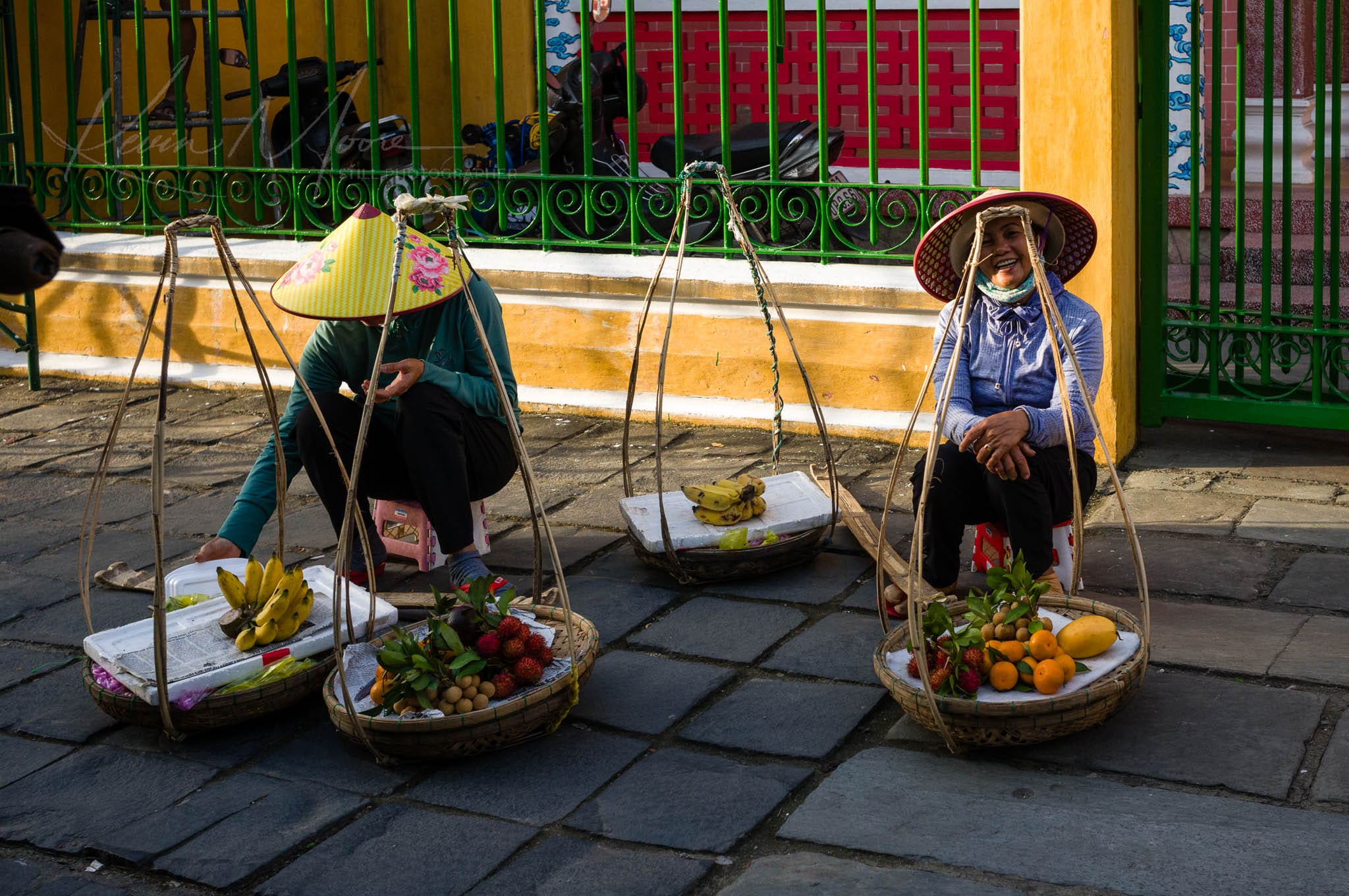 Vietnamese street vendors selling fresh produce from traditional bamboo baskets.