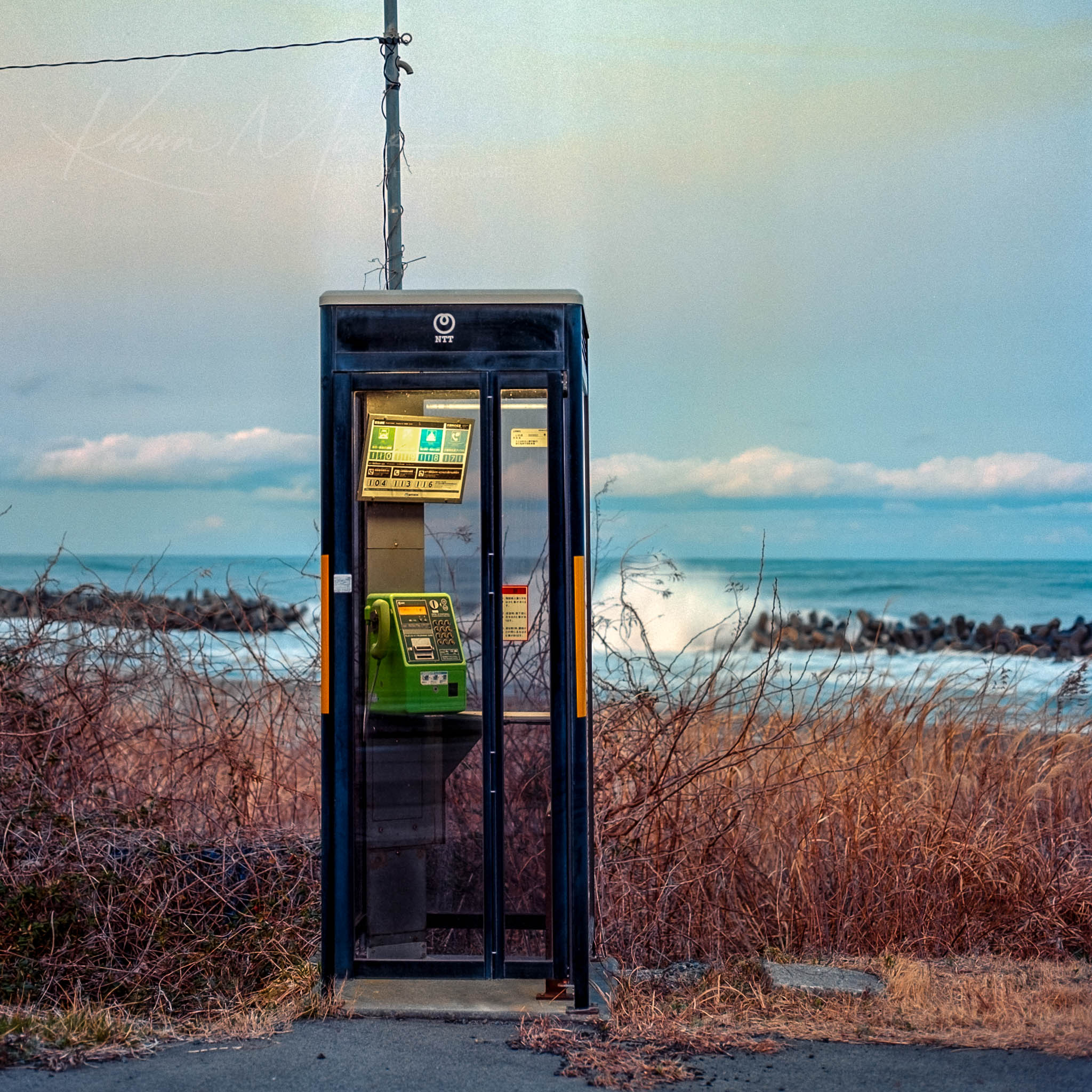 Vintage public phone booth against tranquil rural landscape at twilight.
