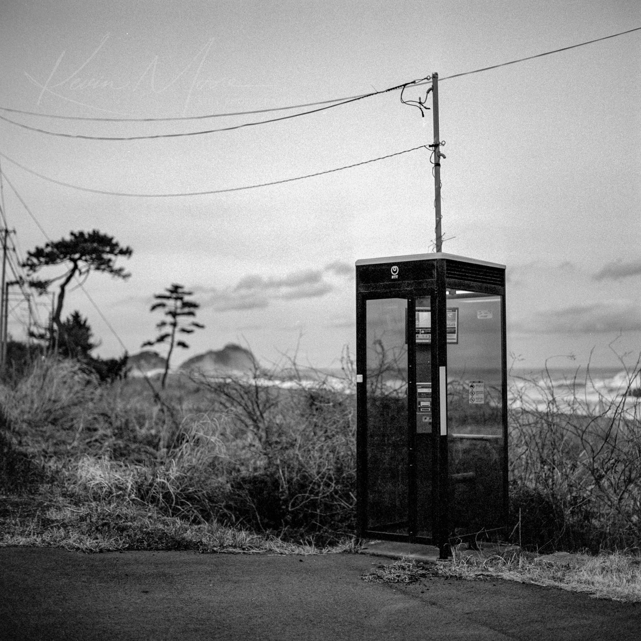 Vintage phone booth in abandoned rural landscape, black and white photography