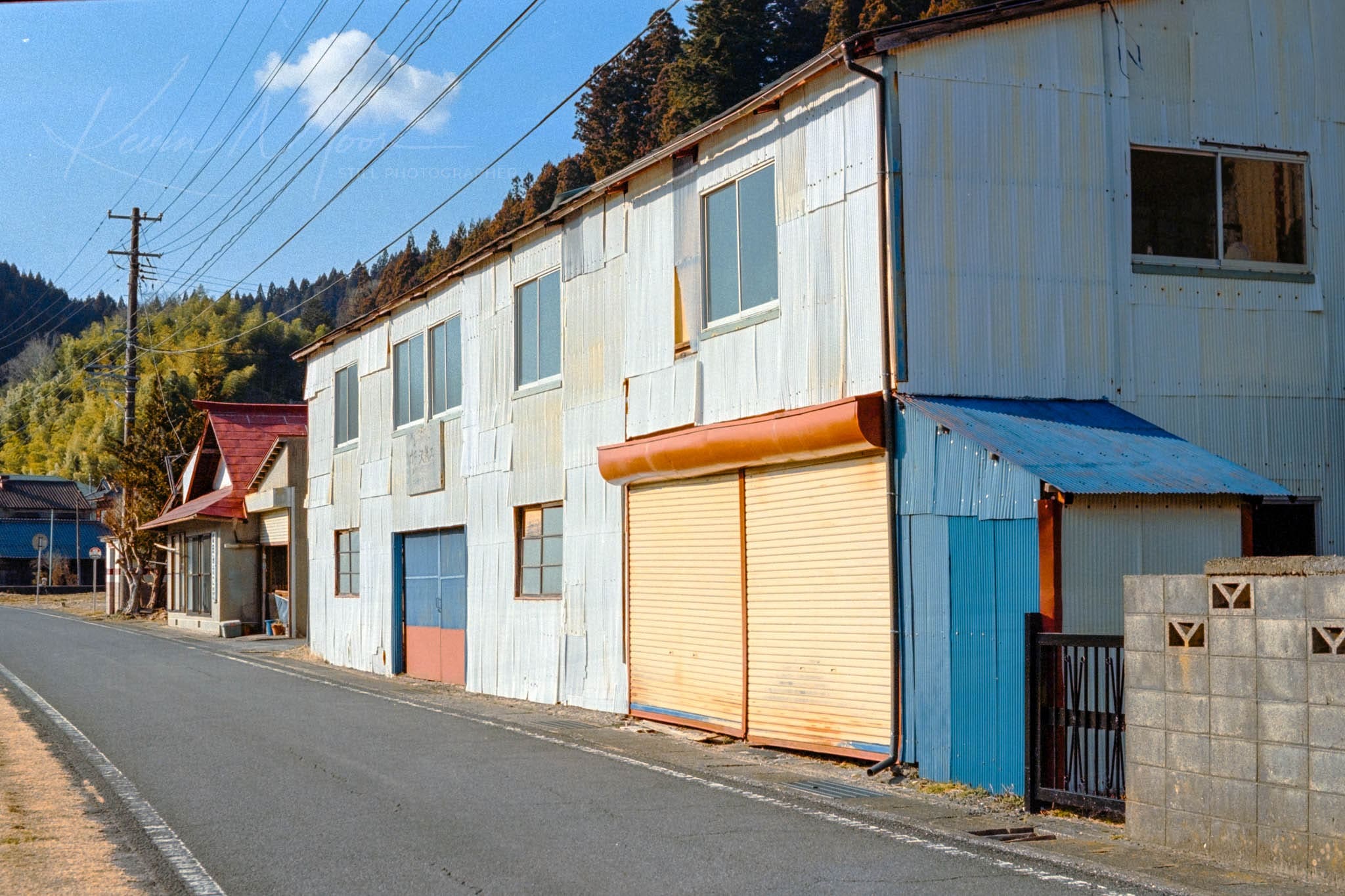 Deserted Street with Weathered Blue Buildings and Red House on Sunny Day