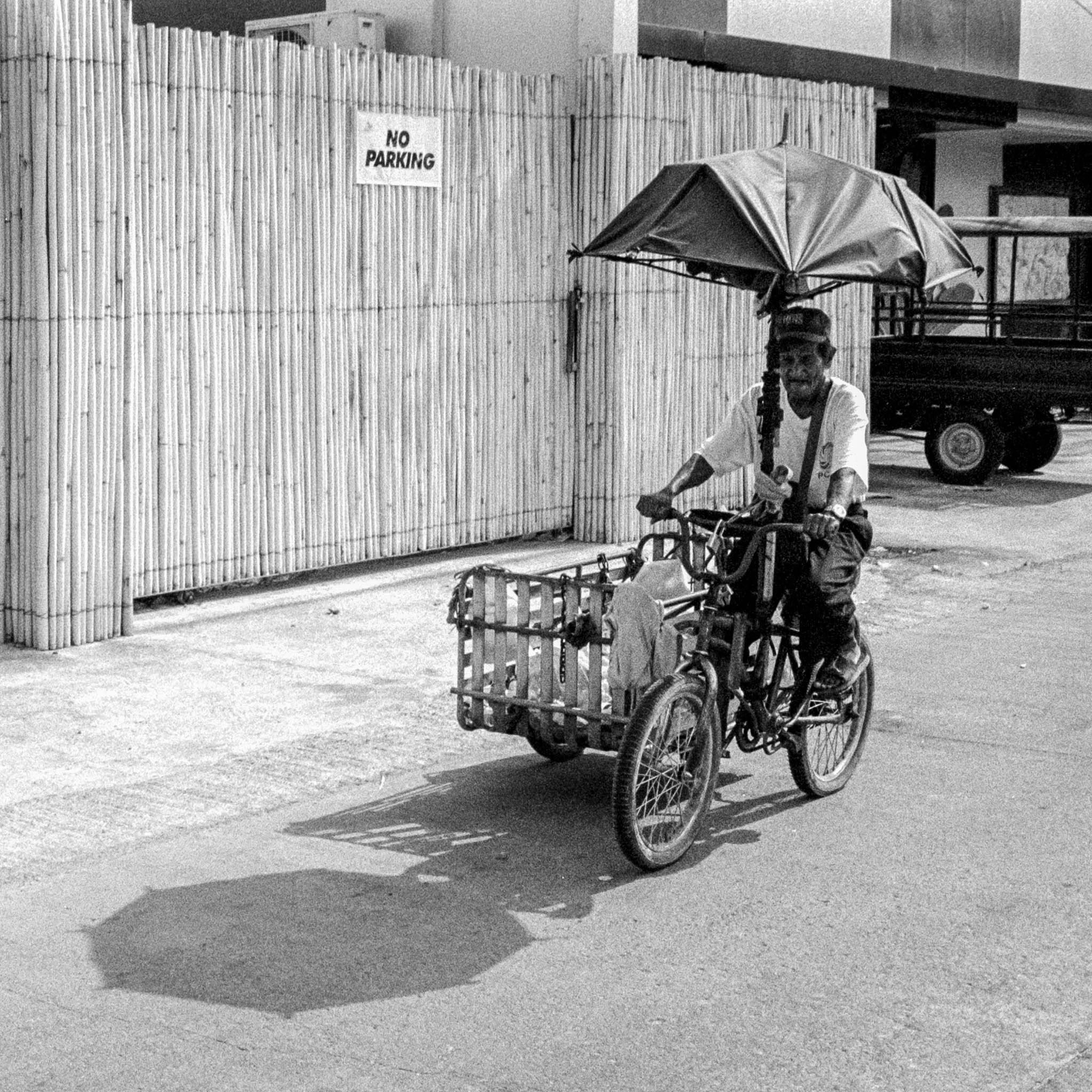 Vintage street vendor selling drinks from a bicycle on a mid-20th-century urban street.