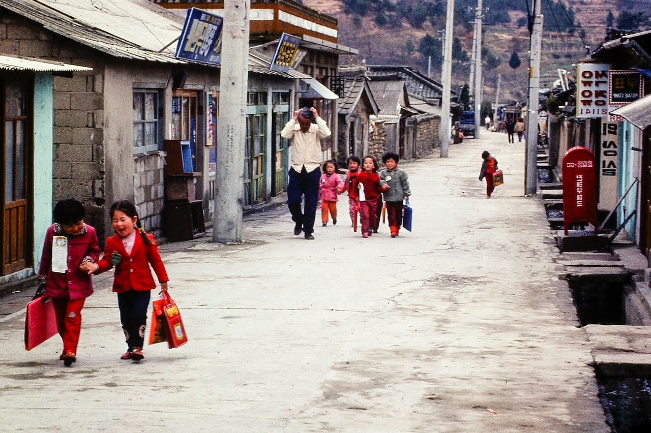 Children enjoying a walk on a traditional Korean street with old-style buildings.