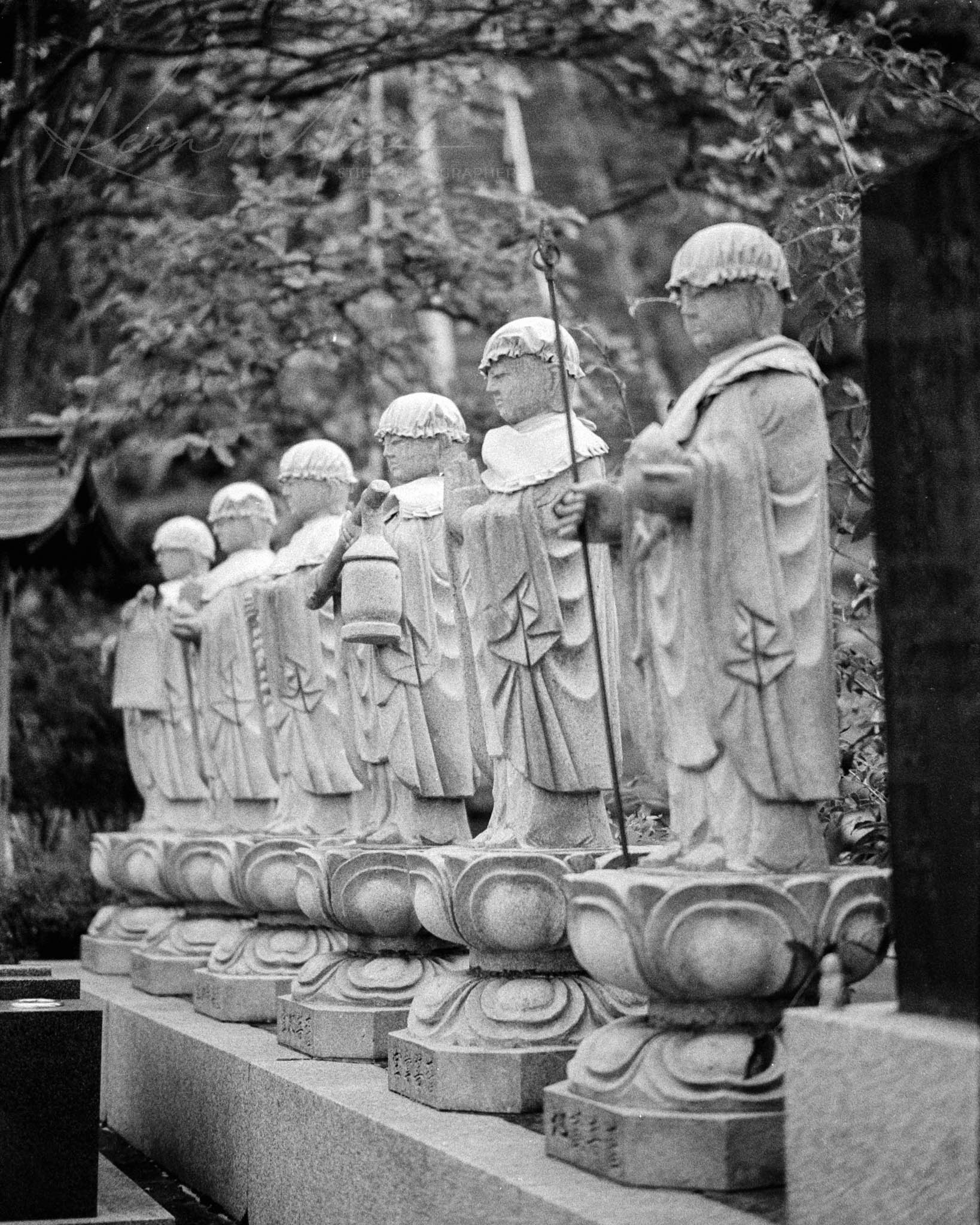 Row of traditional East Asian guardian statues in a timeless black and white setting.