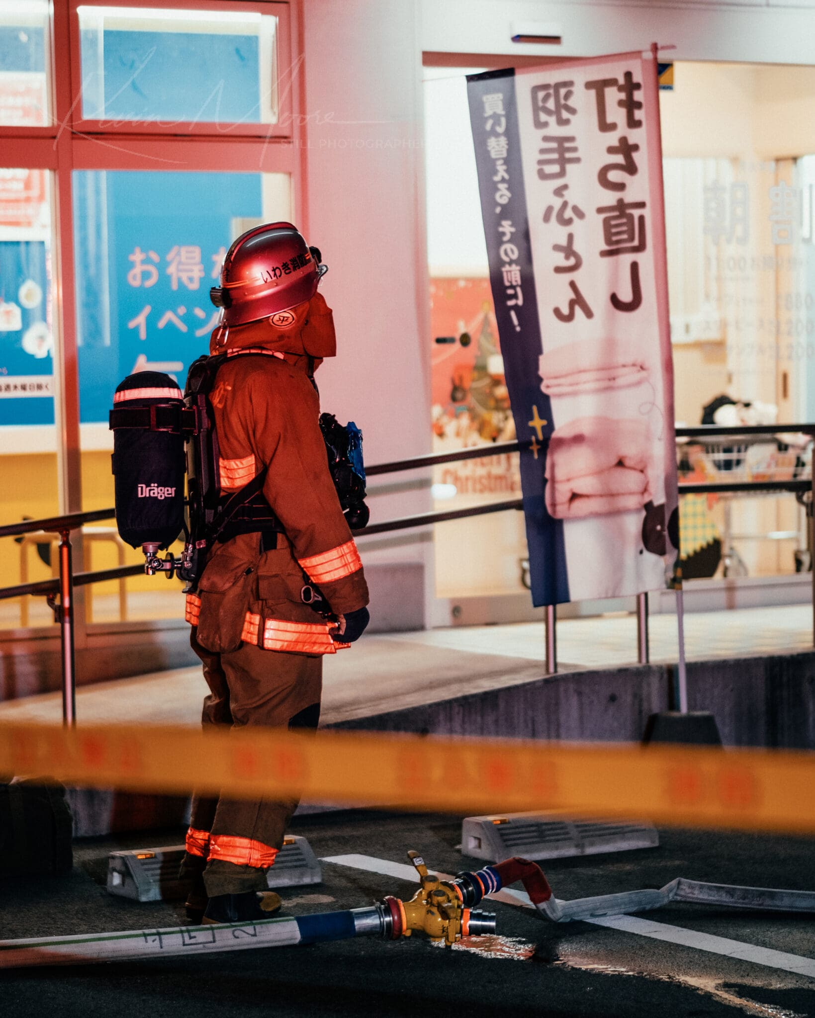 Japanese firefighter in full gear at dawn, ready for emergency at urban site.