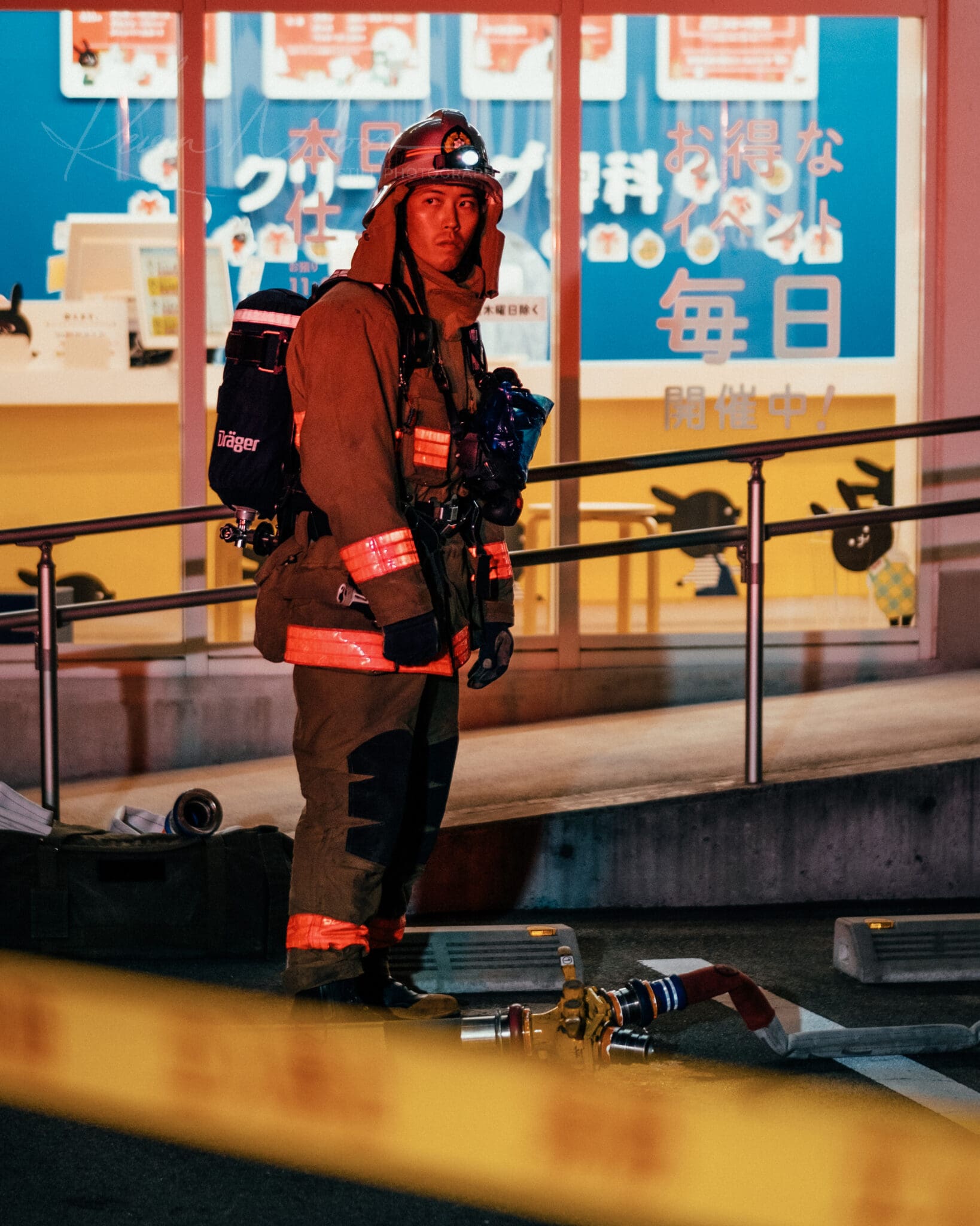 Japanese firefighter in full gear vigilantly monitoring evening urban scene.