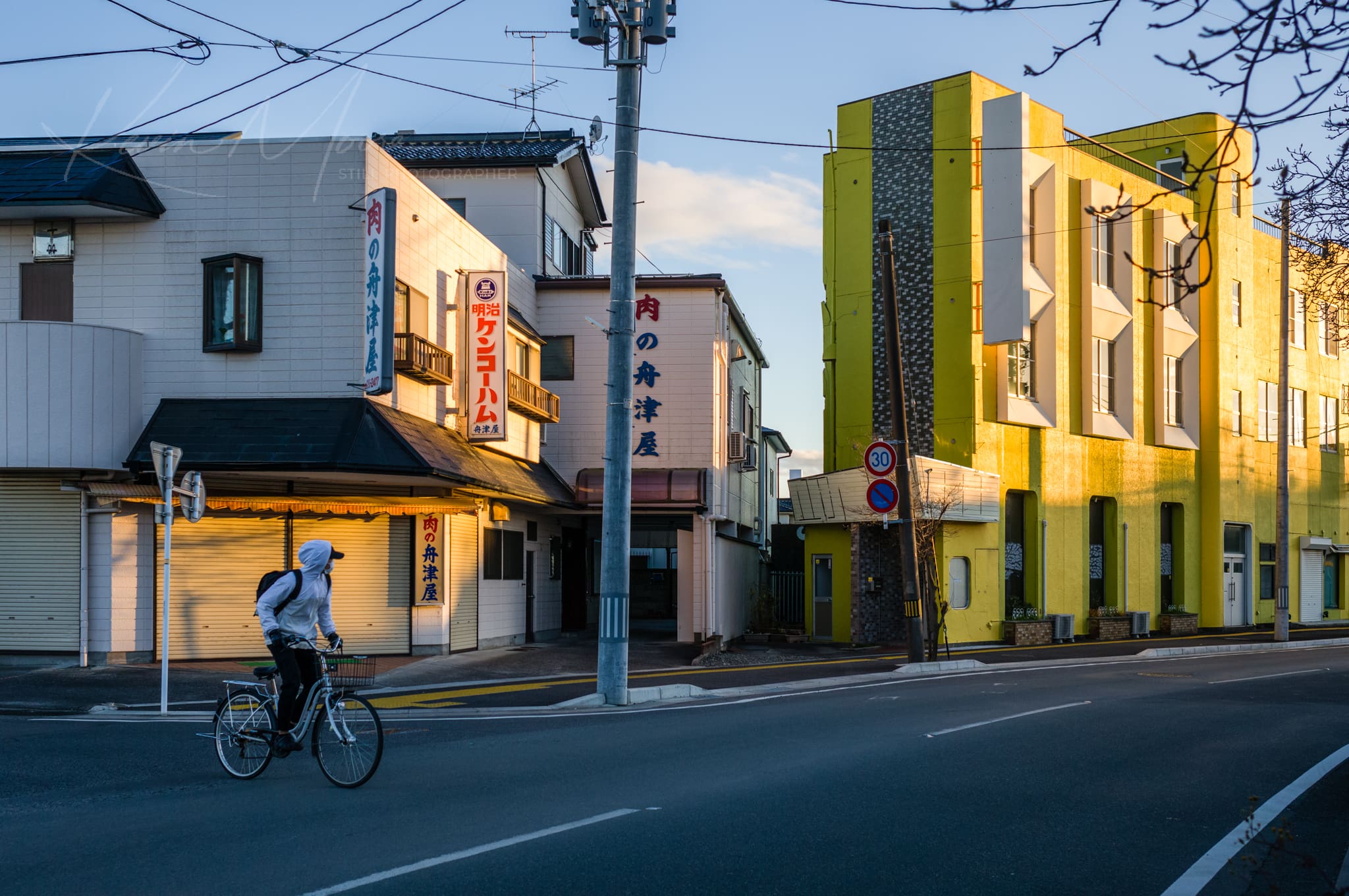 Japanese urban street with a traditional and modern building during golden hour.