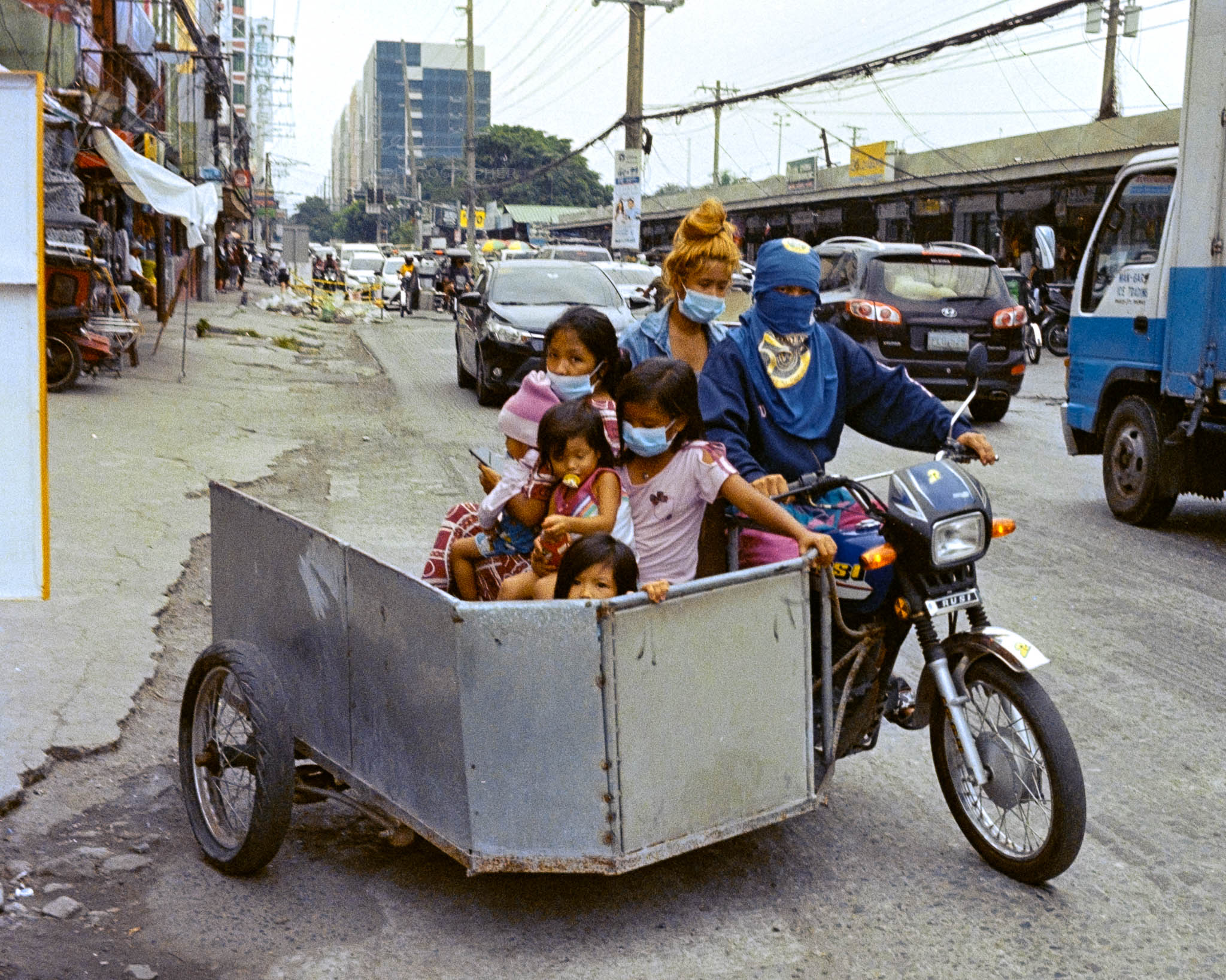 Children commuting in sidecar on busy urban street in developing city.