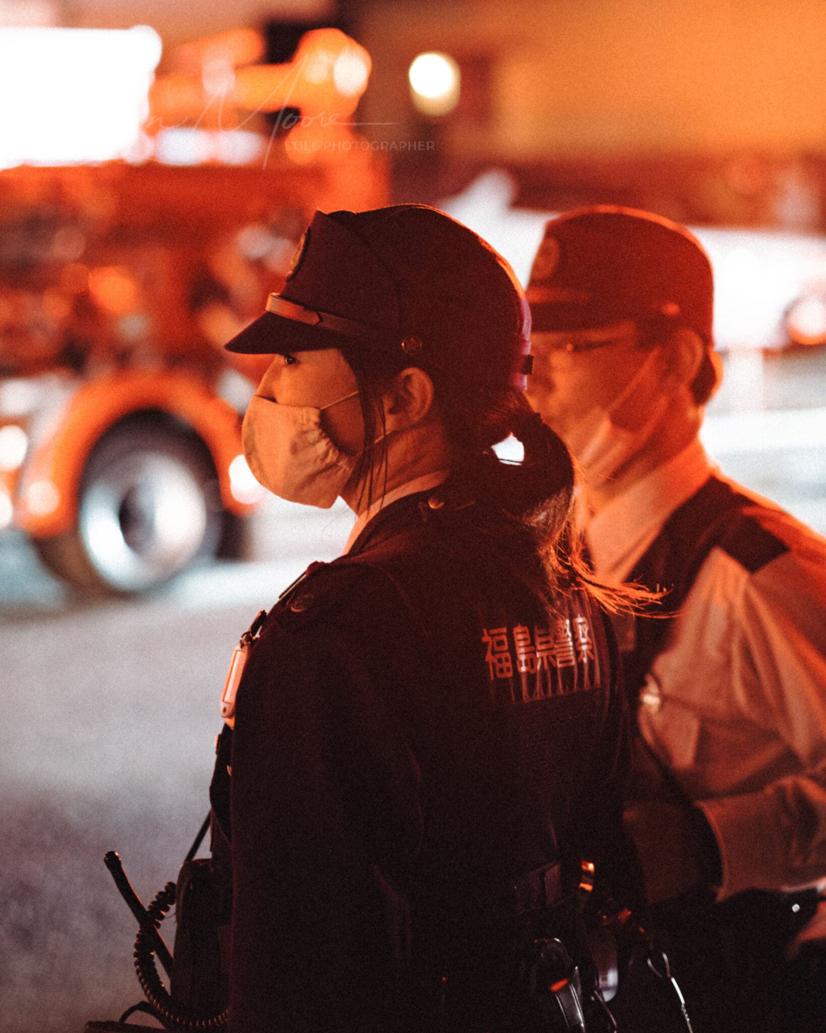 Female police officer on night duty at multi-agency emergency response scene.