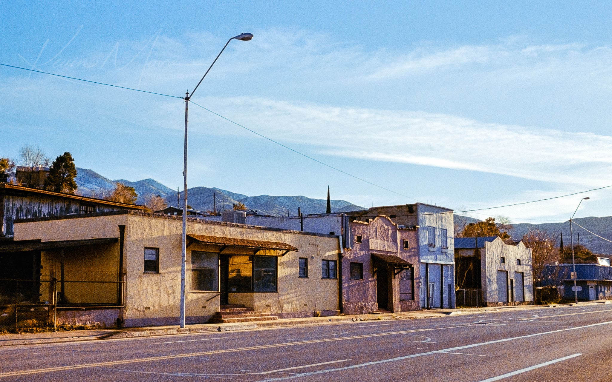 Deserted suburban street scene in a rustic mountain town under clear skies.