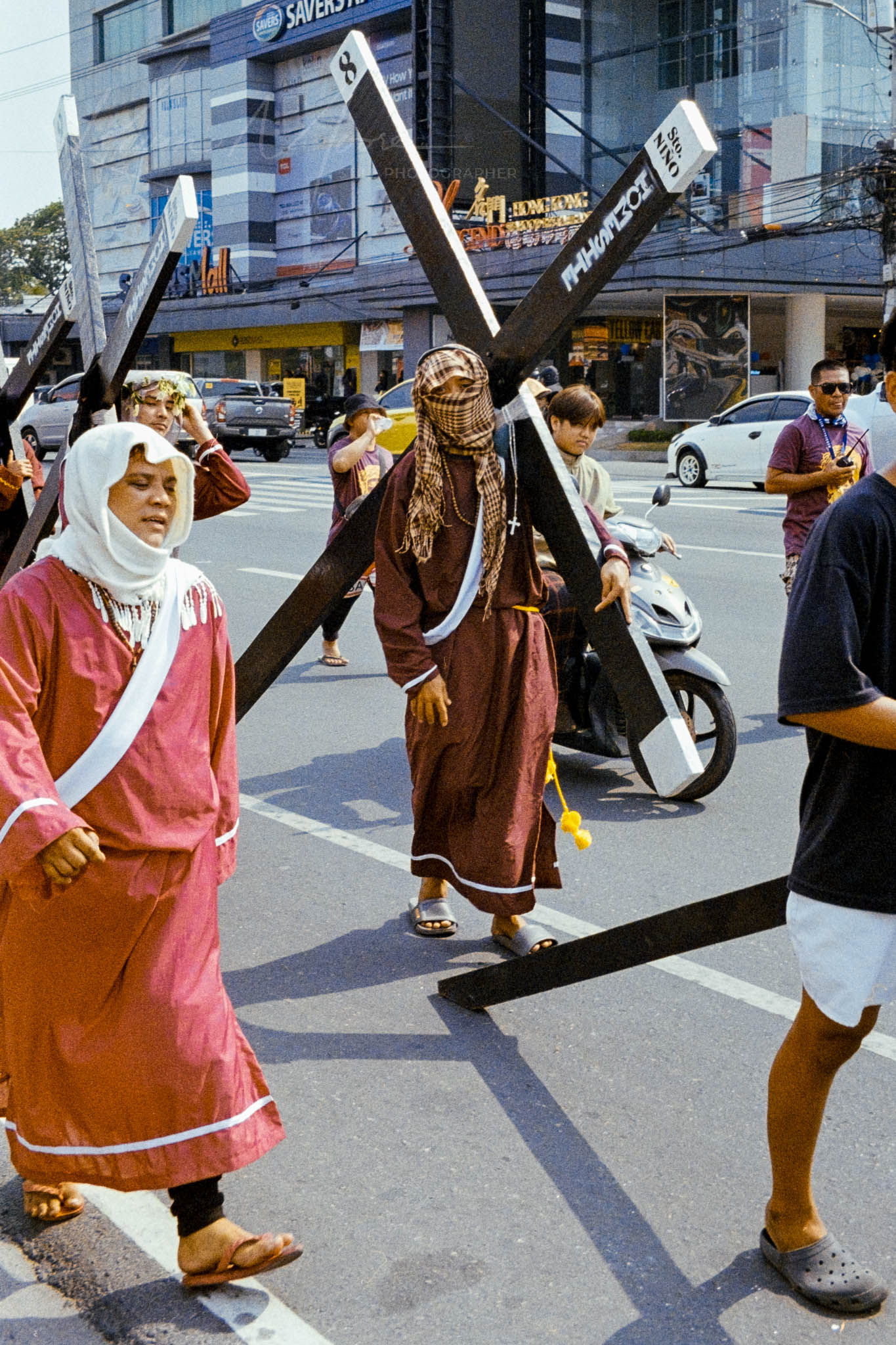 Barefoot participants in traditional attire during a religious procession on a modern city street.
