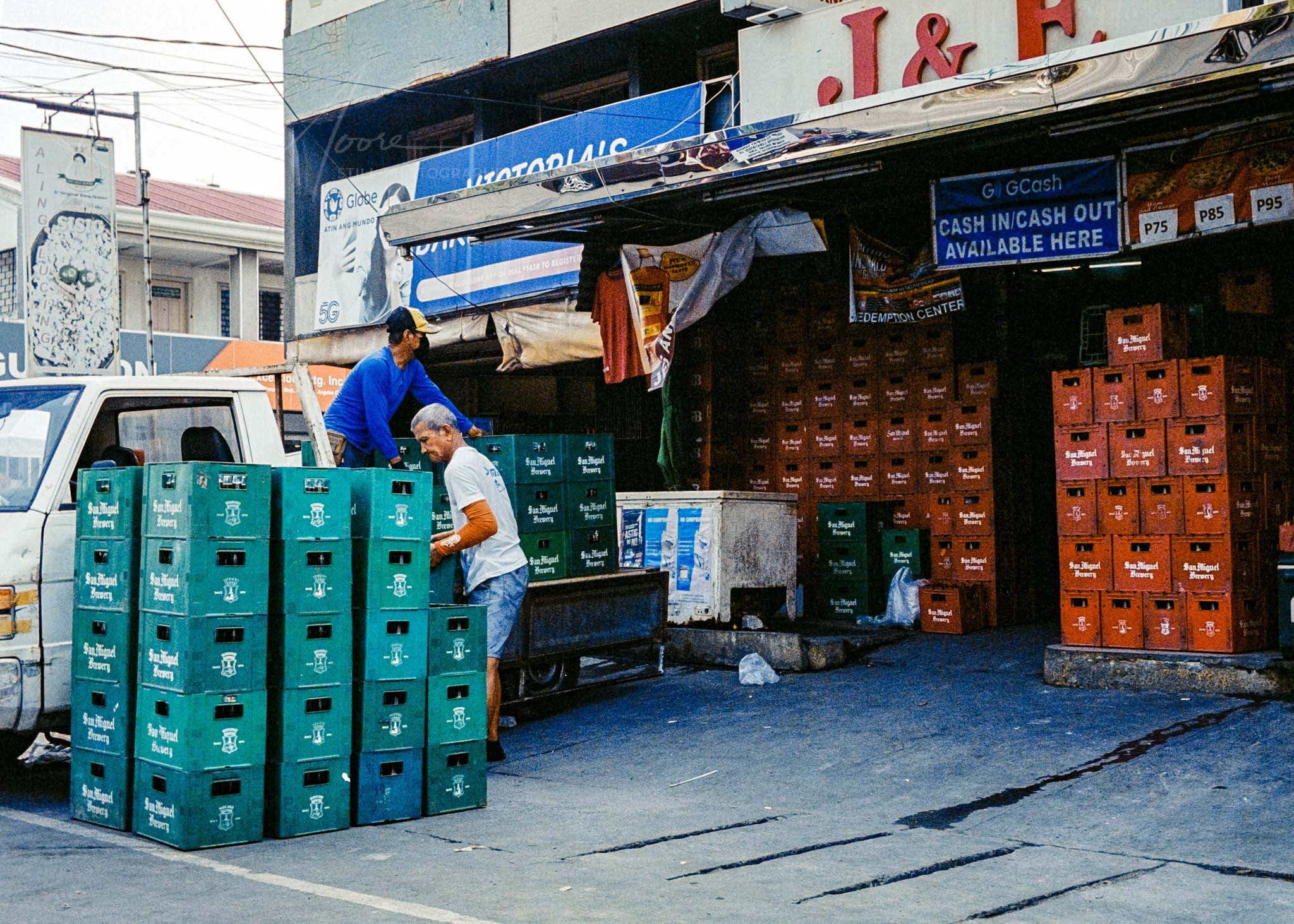 Workers handling green crates at a busy San Miguiel Beer distribution center.