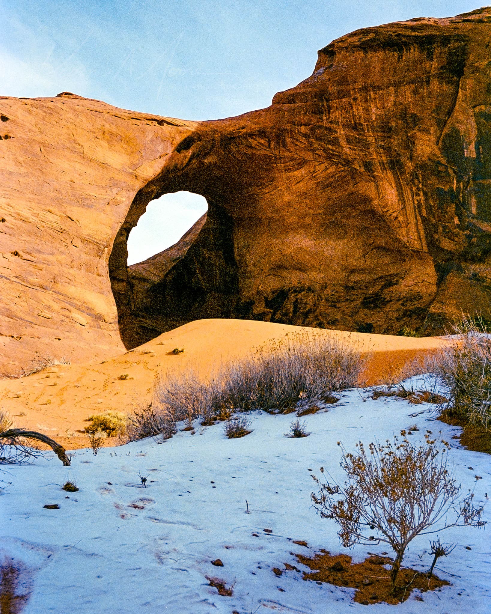 Majestic winter-kissed sandstone arch showcasing geological beauty under a stark clear sky.