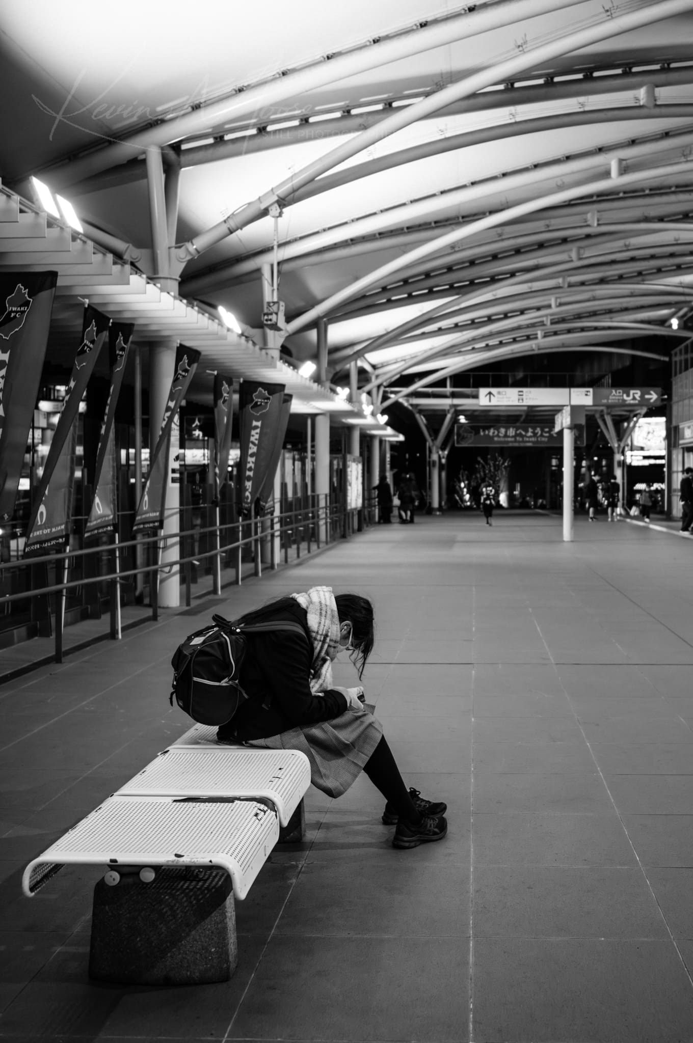 Lonely individual reading at a modern, architectural train station.
