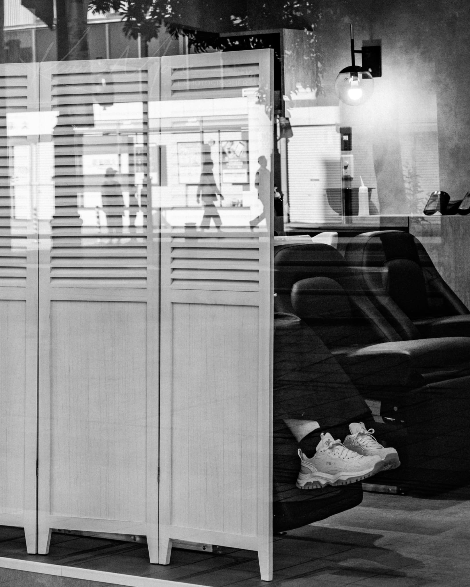 Black and white image of a cozy salon interior with room divider and street view.