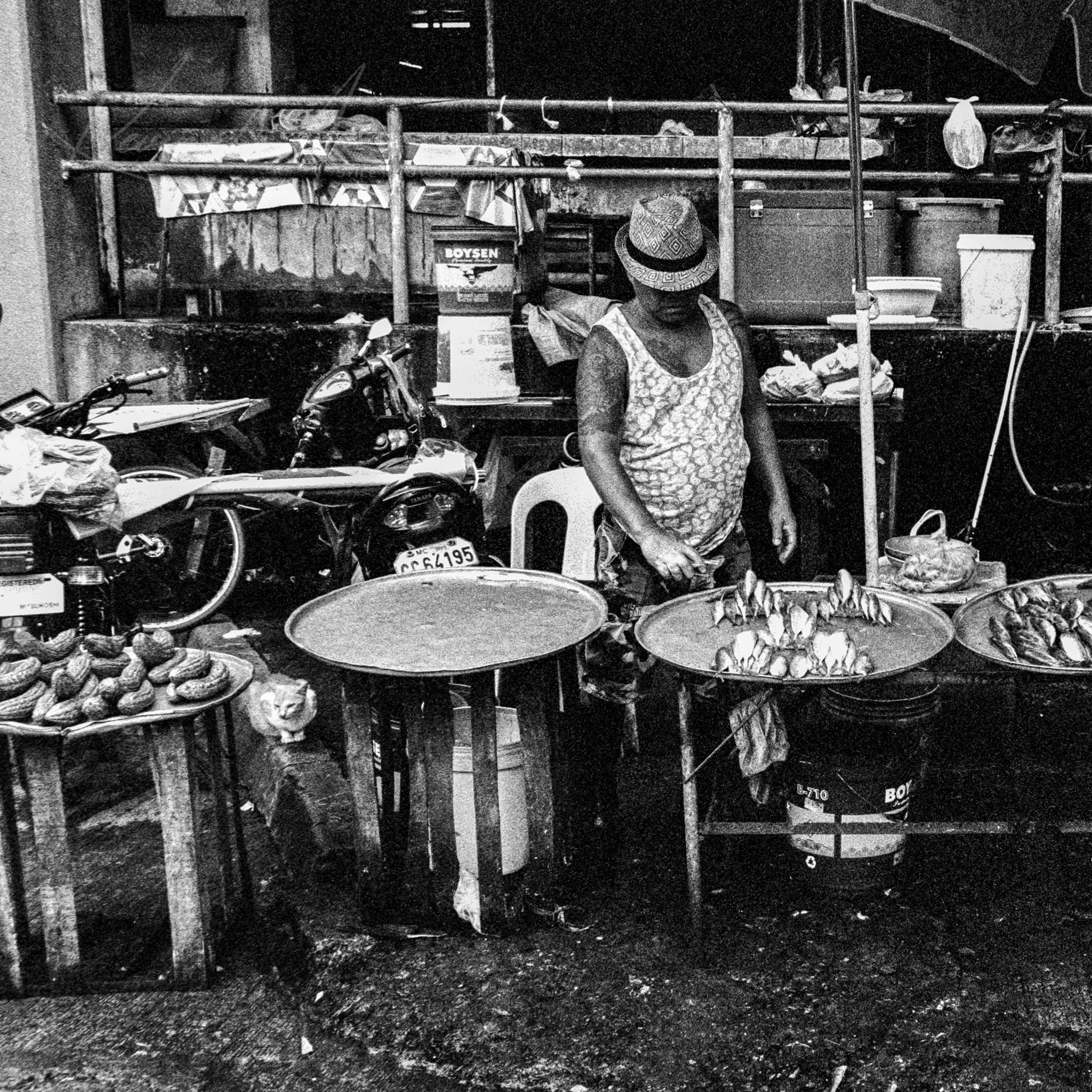 Monochrome shot of a bustling outdoor street food market with a busy vendor at work.