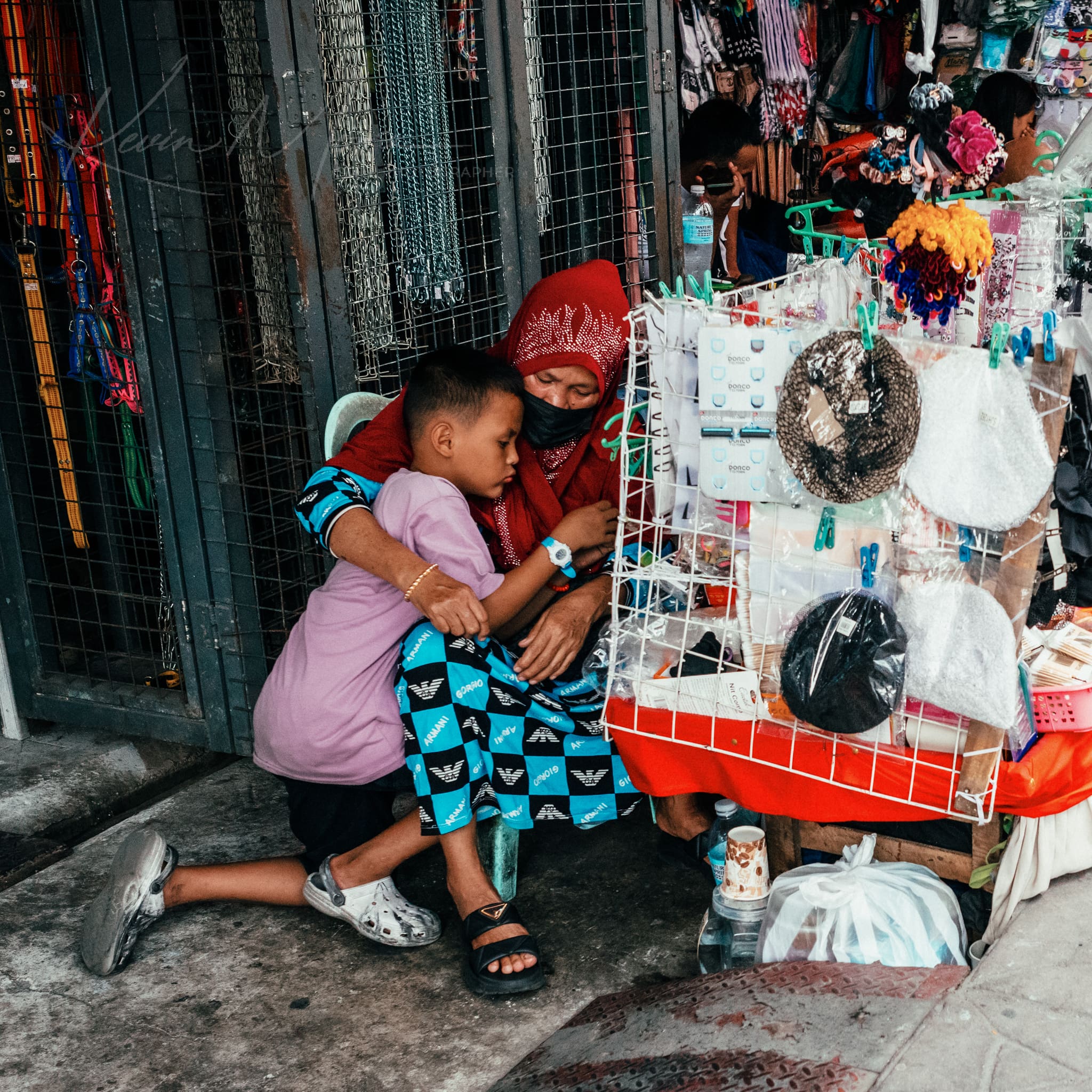 Street vendor in a red headscarf engaging with a young boy amidst a busy Philippines marketplace.
