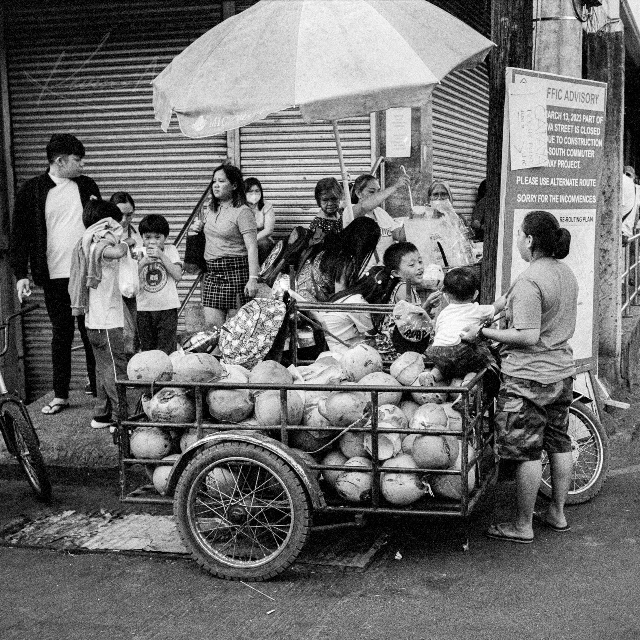 Bustling Street Market Scene, Vendor Selling Fresh Fruits from Cart in Black and White Photo