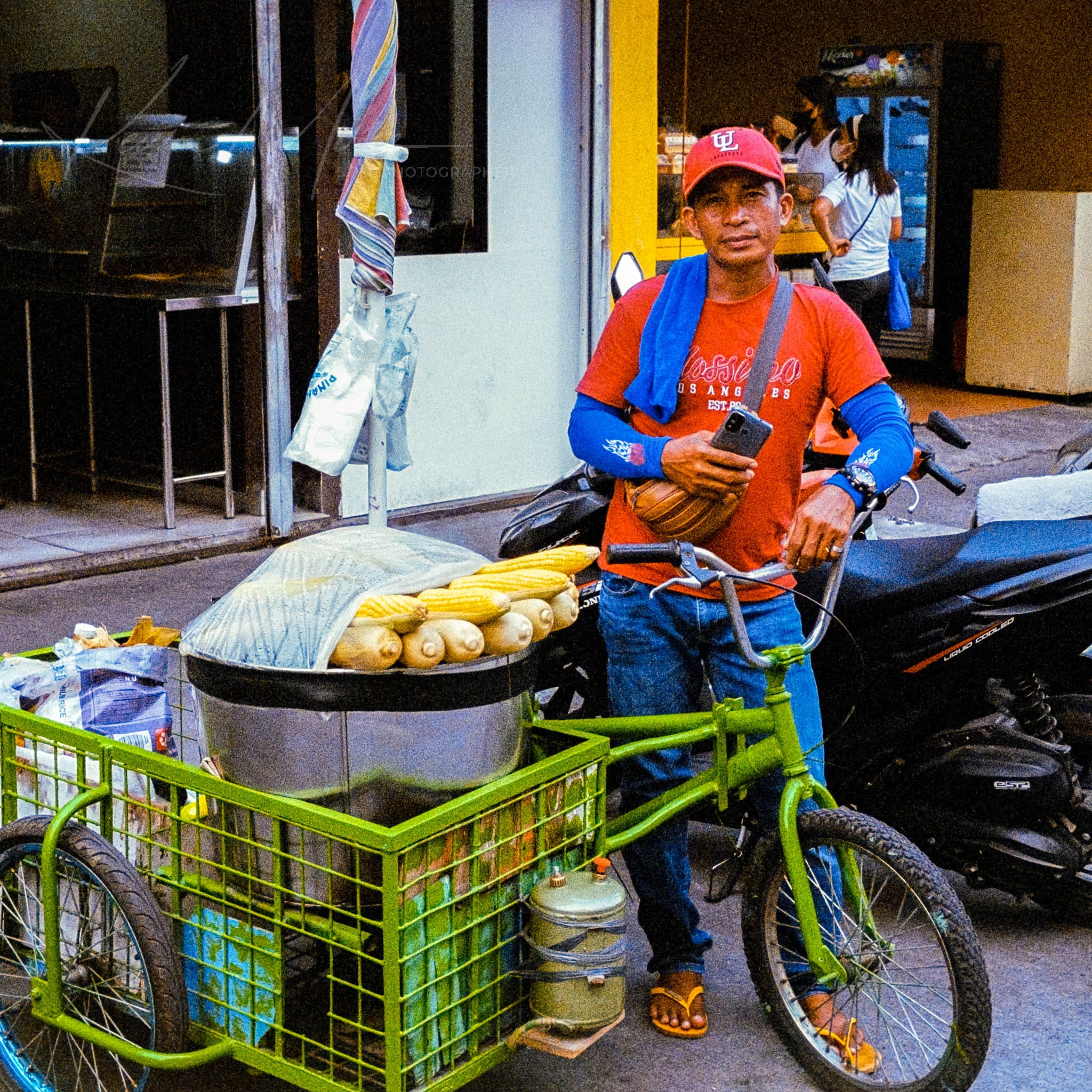 Street vendor with coconut-laden bicycle in vibrant Southeast Asian urban setting.