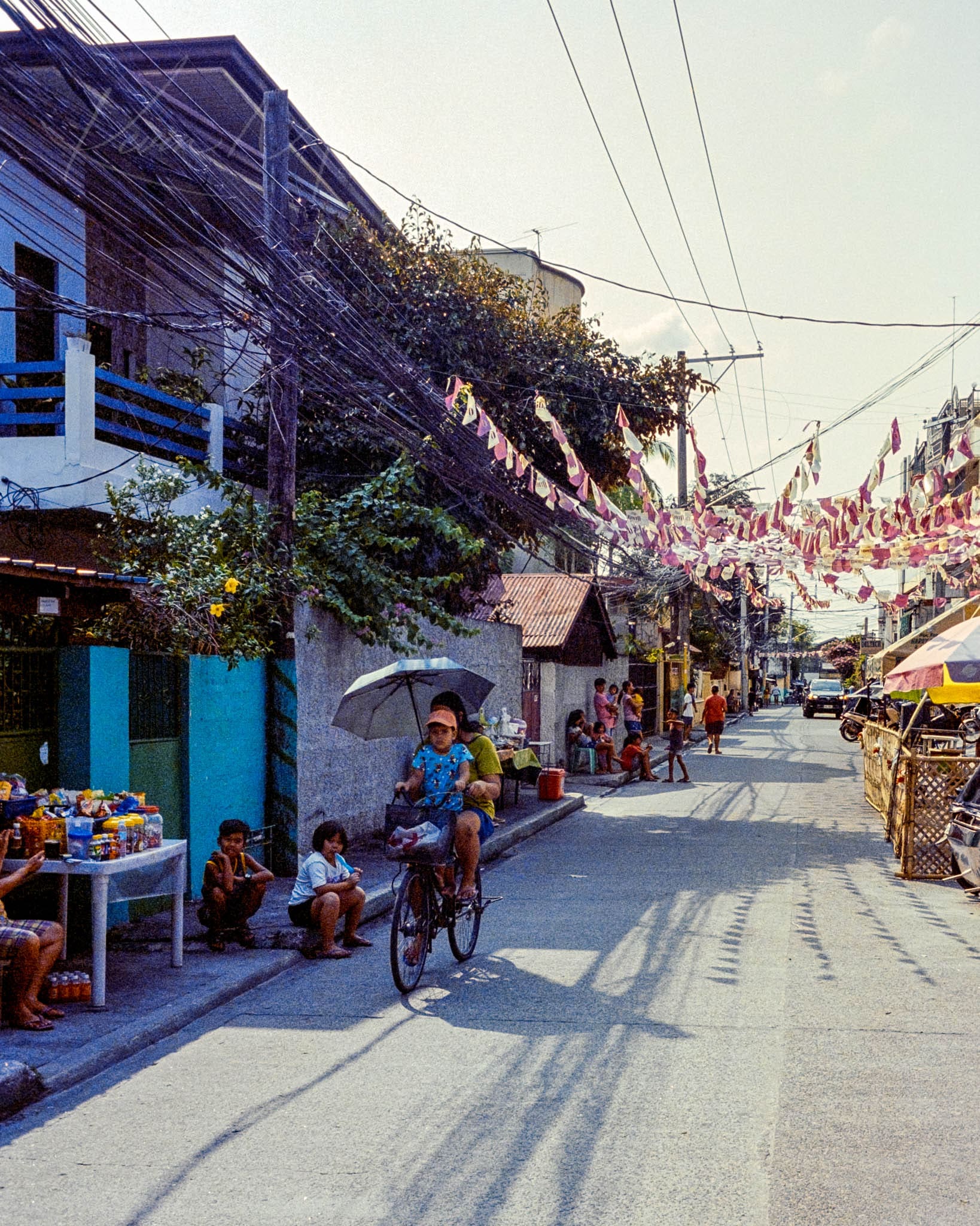 Bustling Sunny Street with Cyclist, Pedestrians and Local Shops in Warm Philippines