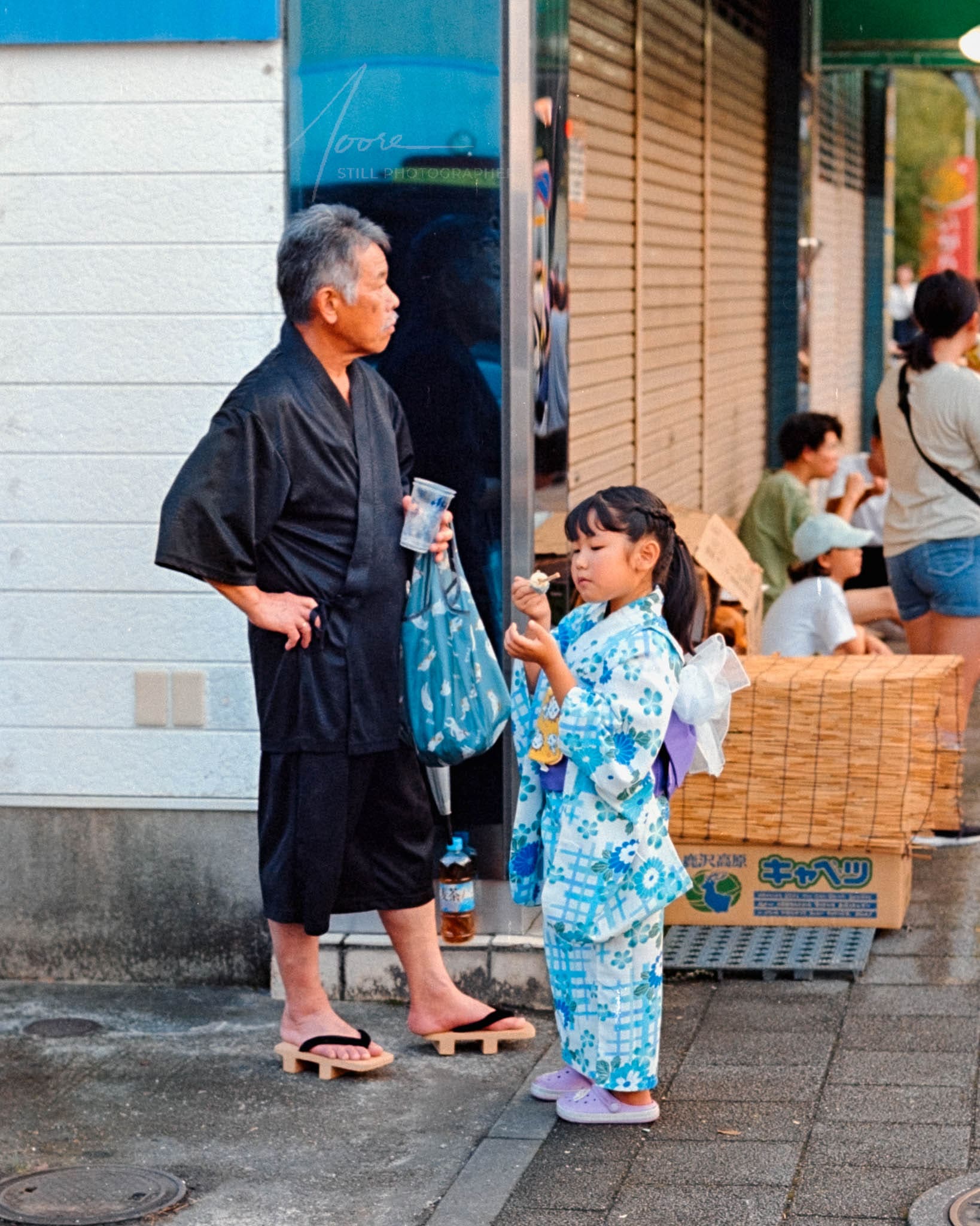 Old man and young girl in traditional Japanese yukata on urban sidewalk, blending culture and modernity.