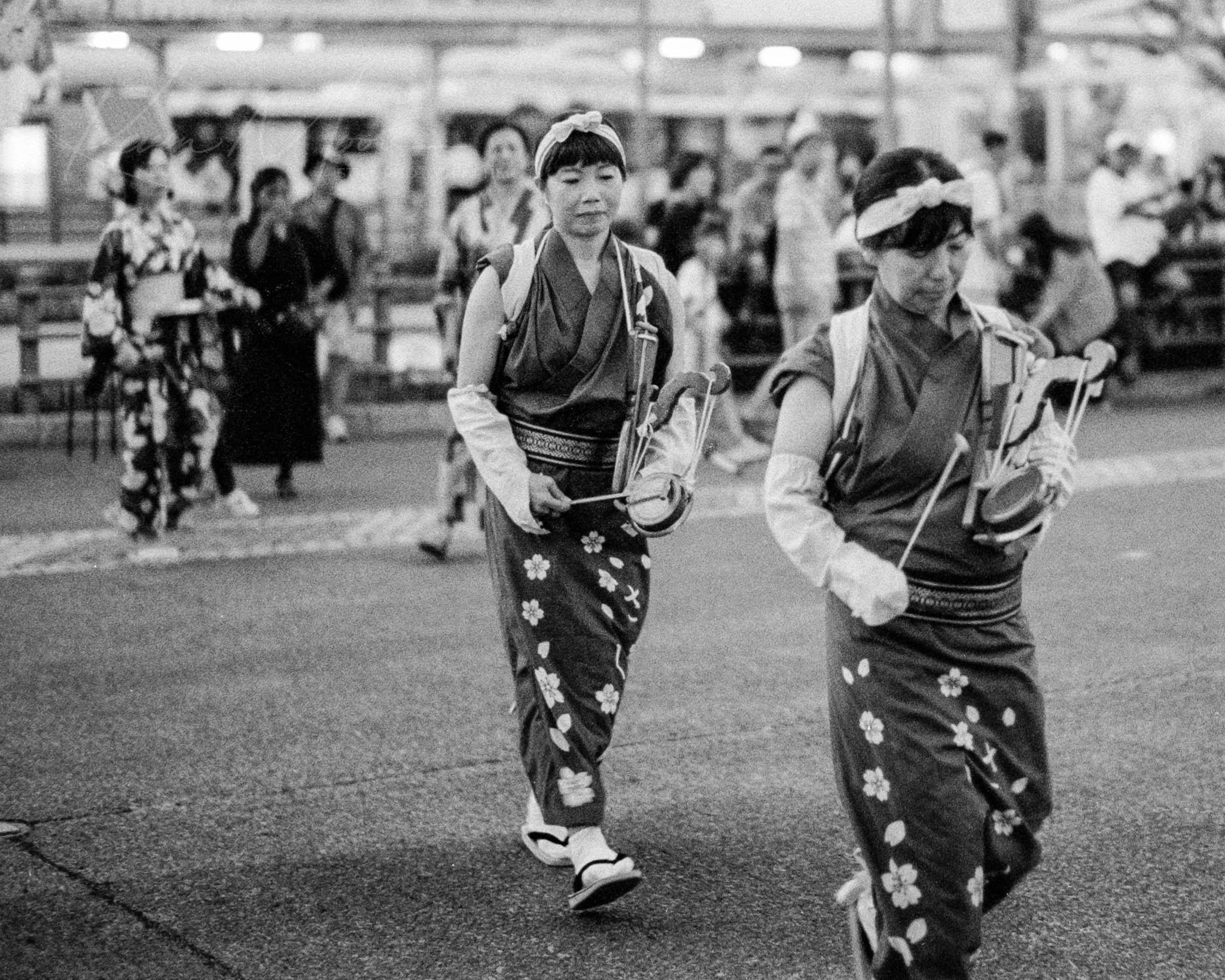 Jangara in traditional attire at a nighttime Japanese festival, captured in black and white.