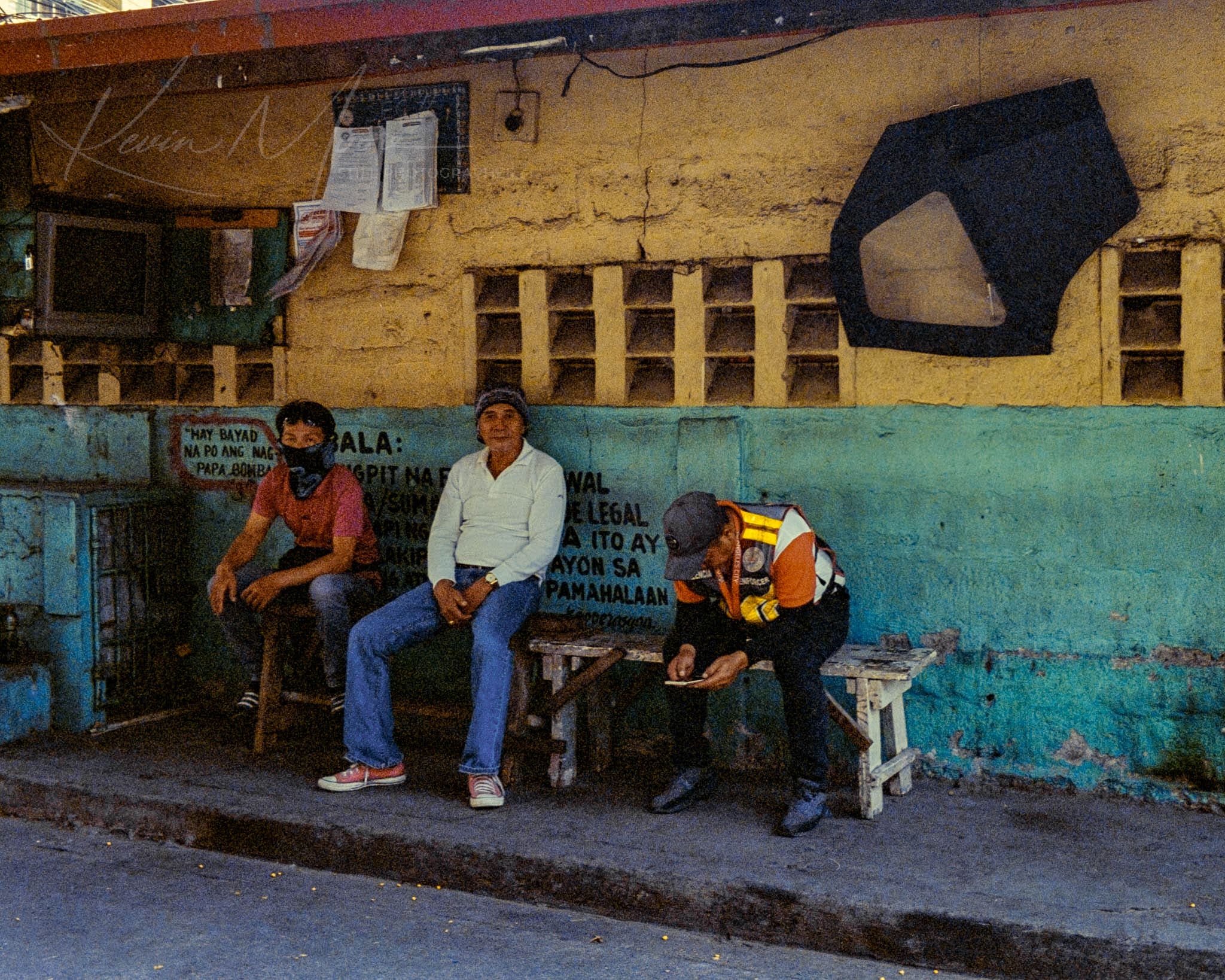 Locals enjoying downtime on makeshift benches in a vibrant, urban community setting.