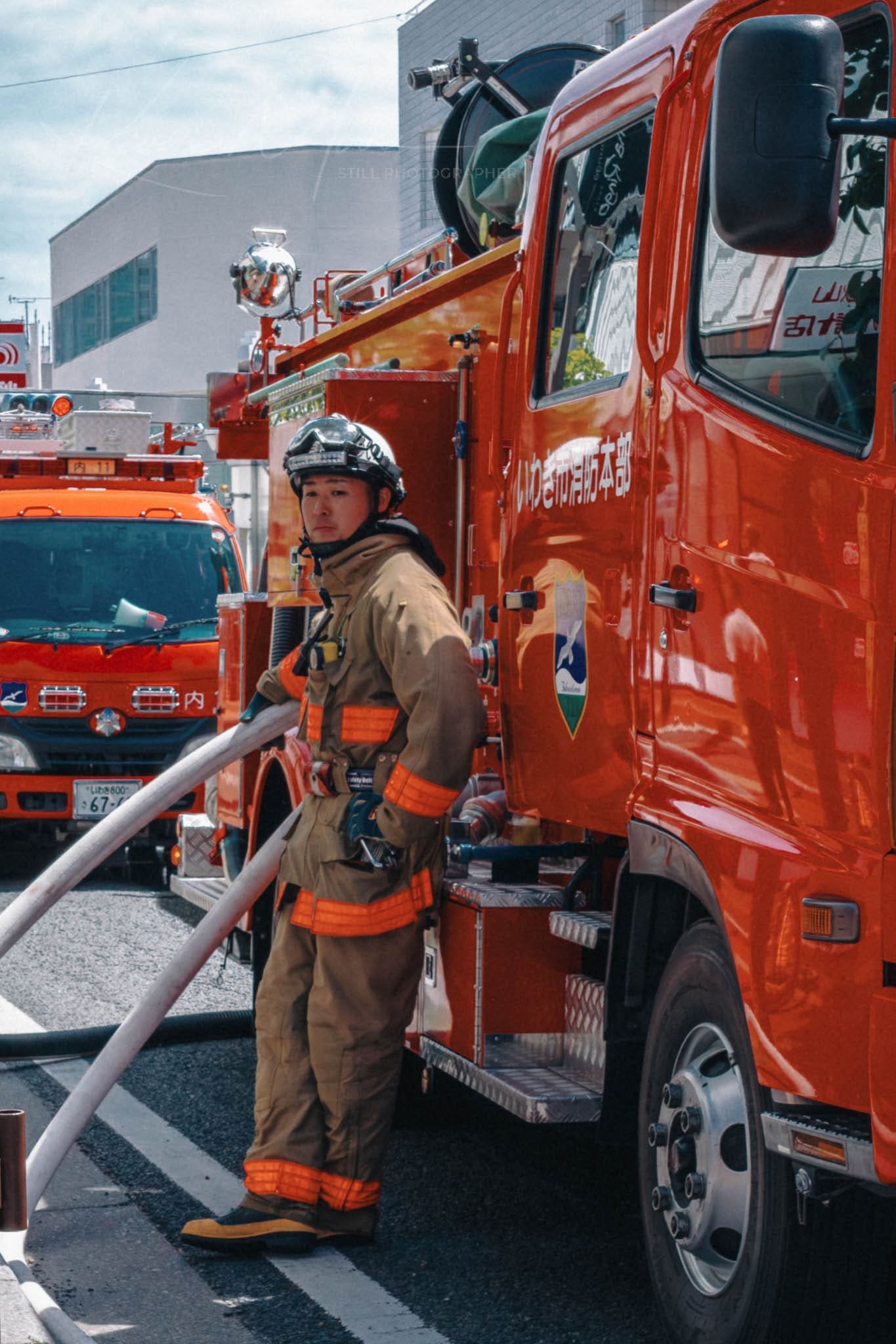 Firefighter in gear ready by red fire engine during emergency.